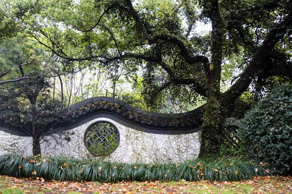 A traditional Chinese garden wall with undulating roof and circular