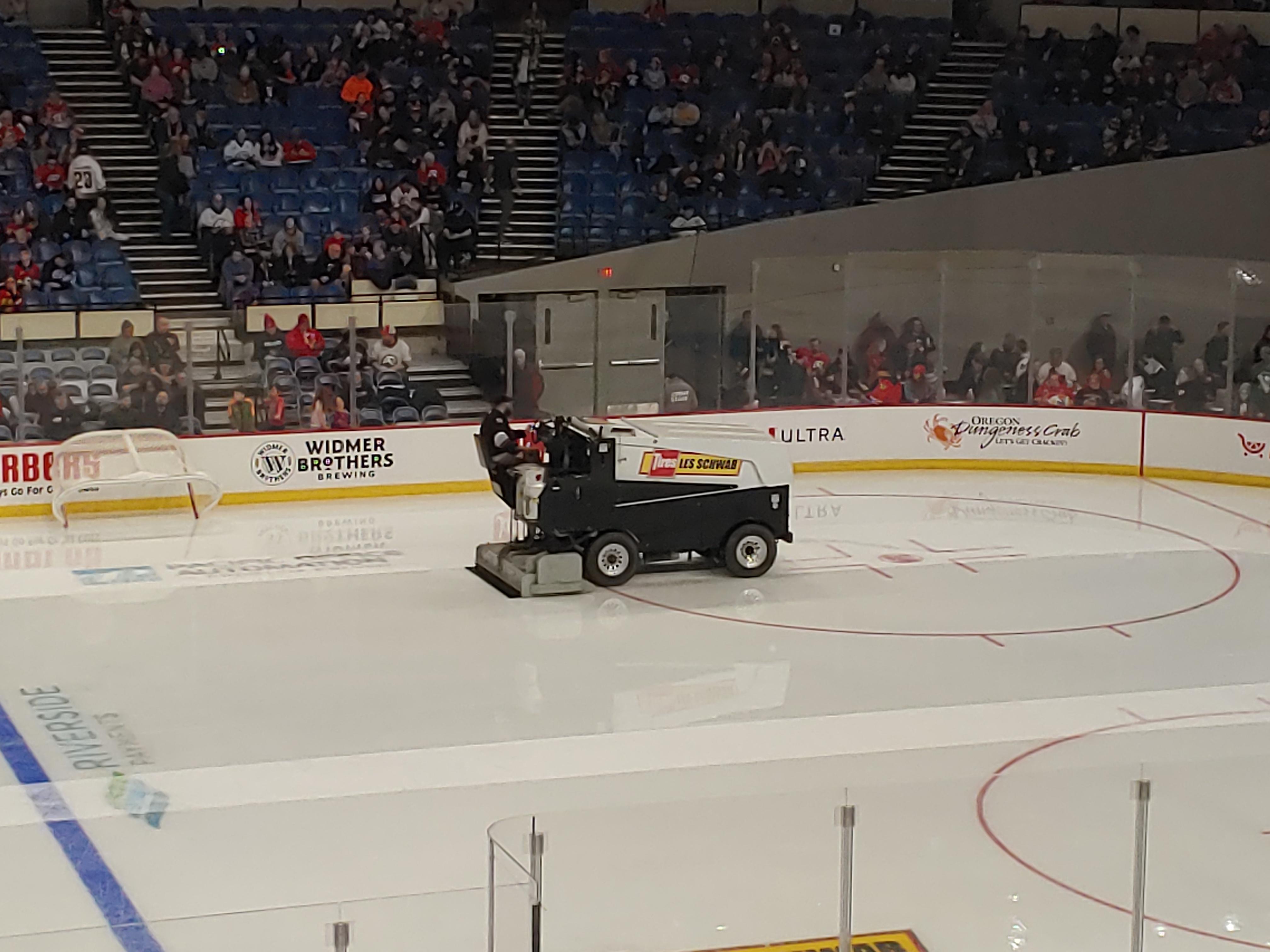The smooth, reflective surface of ice behind the Zamboni. r