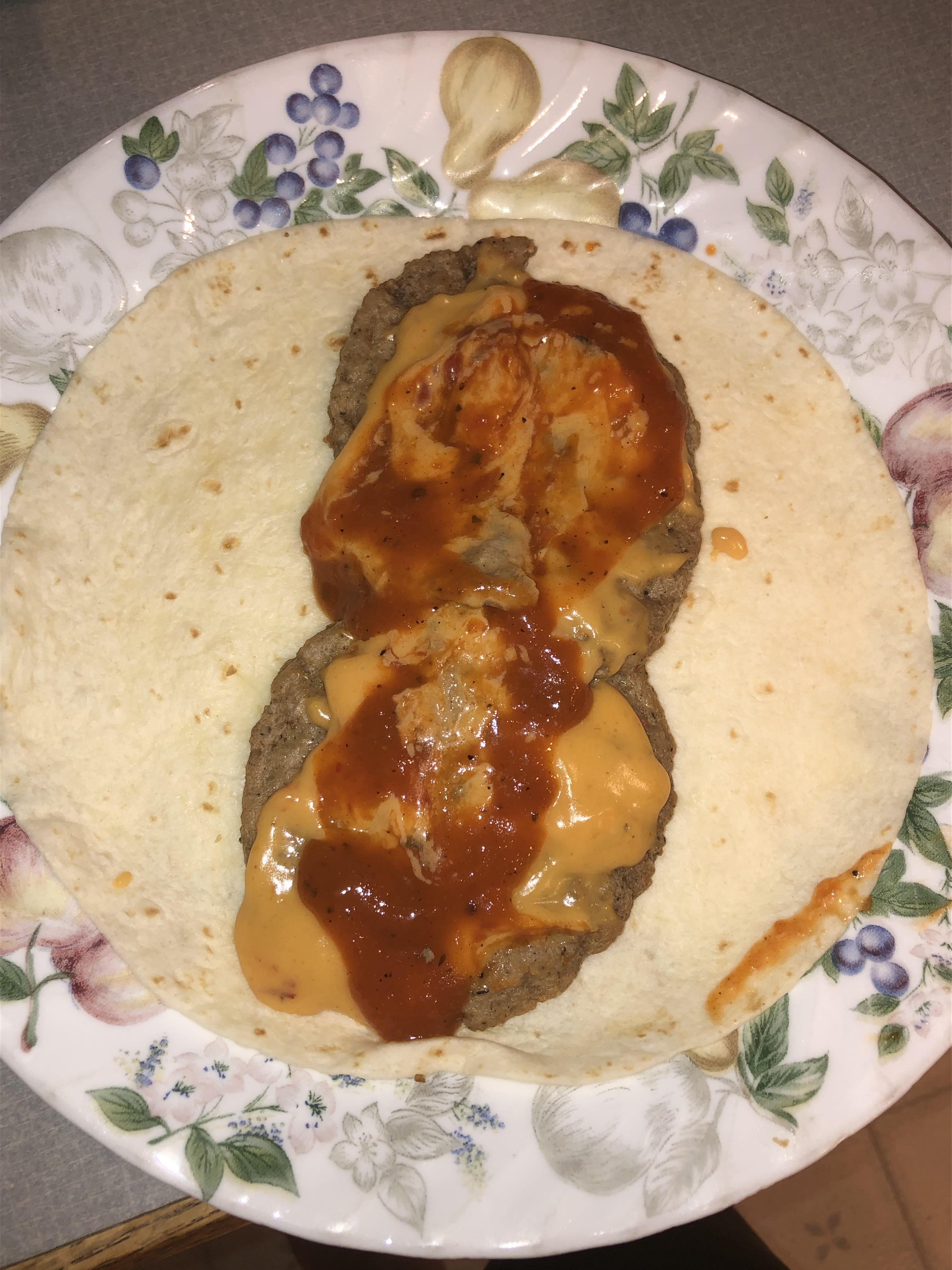 Breakfast sausage patty burrito with queso and aardvark sauce r