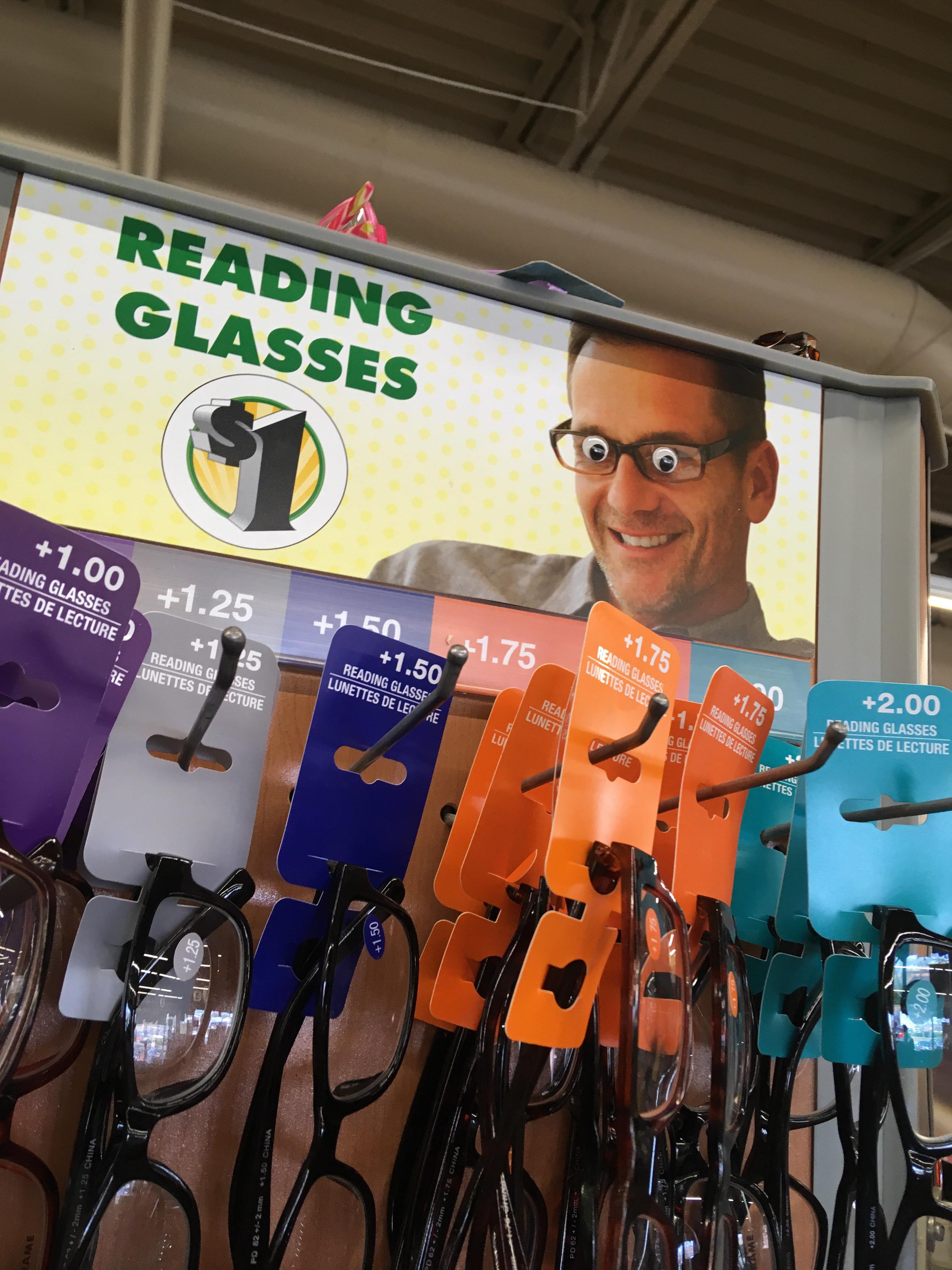 Someone glued googley eyes on the reading glasses sign at the Dollar
