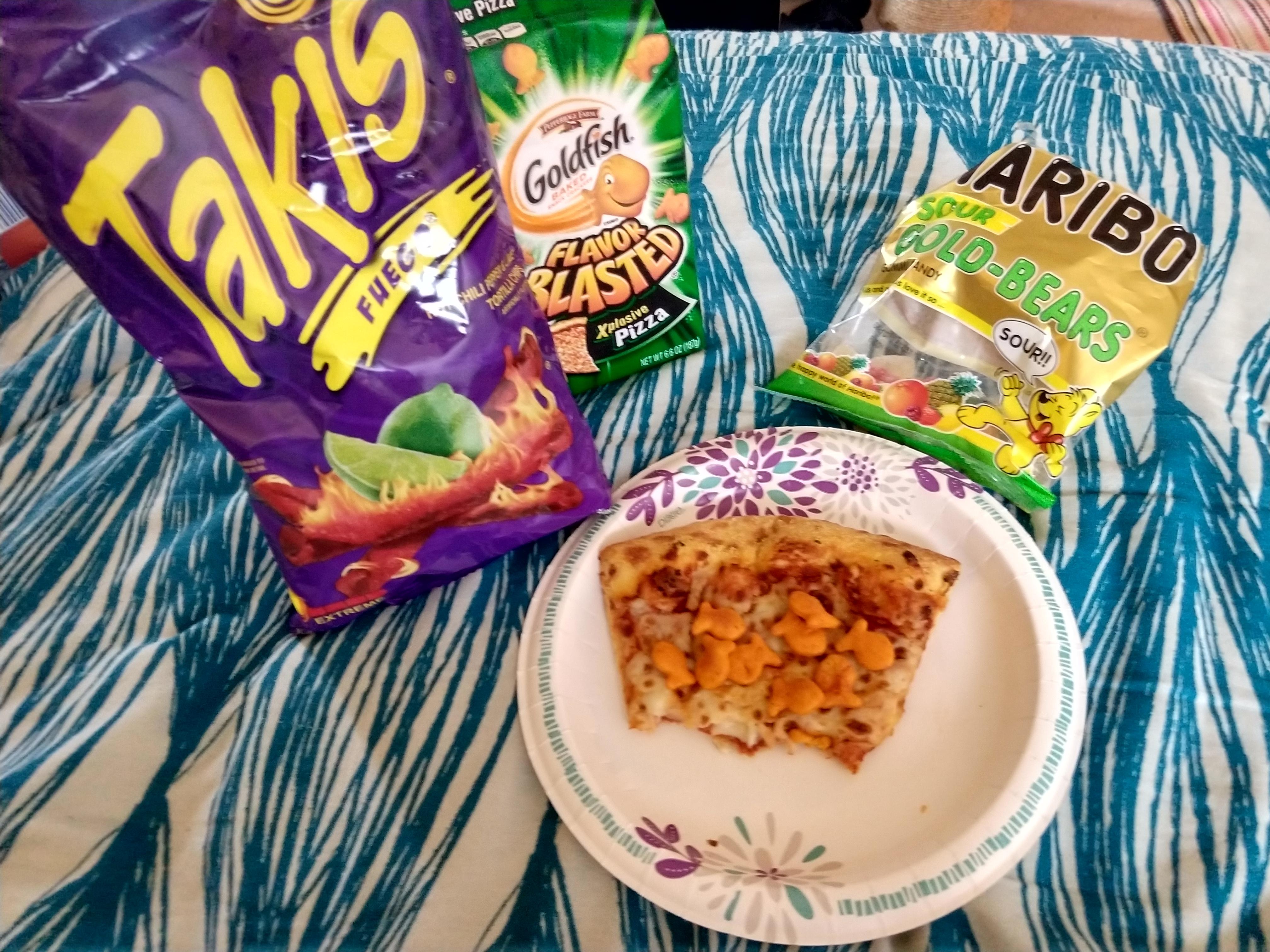 Pizza Goldfish pizza with a side of takis and gummy bears, in bed on a paper plate. r