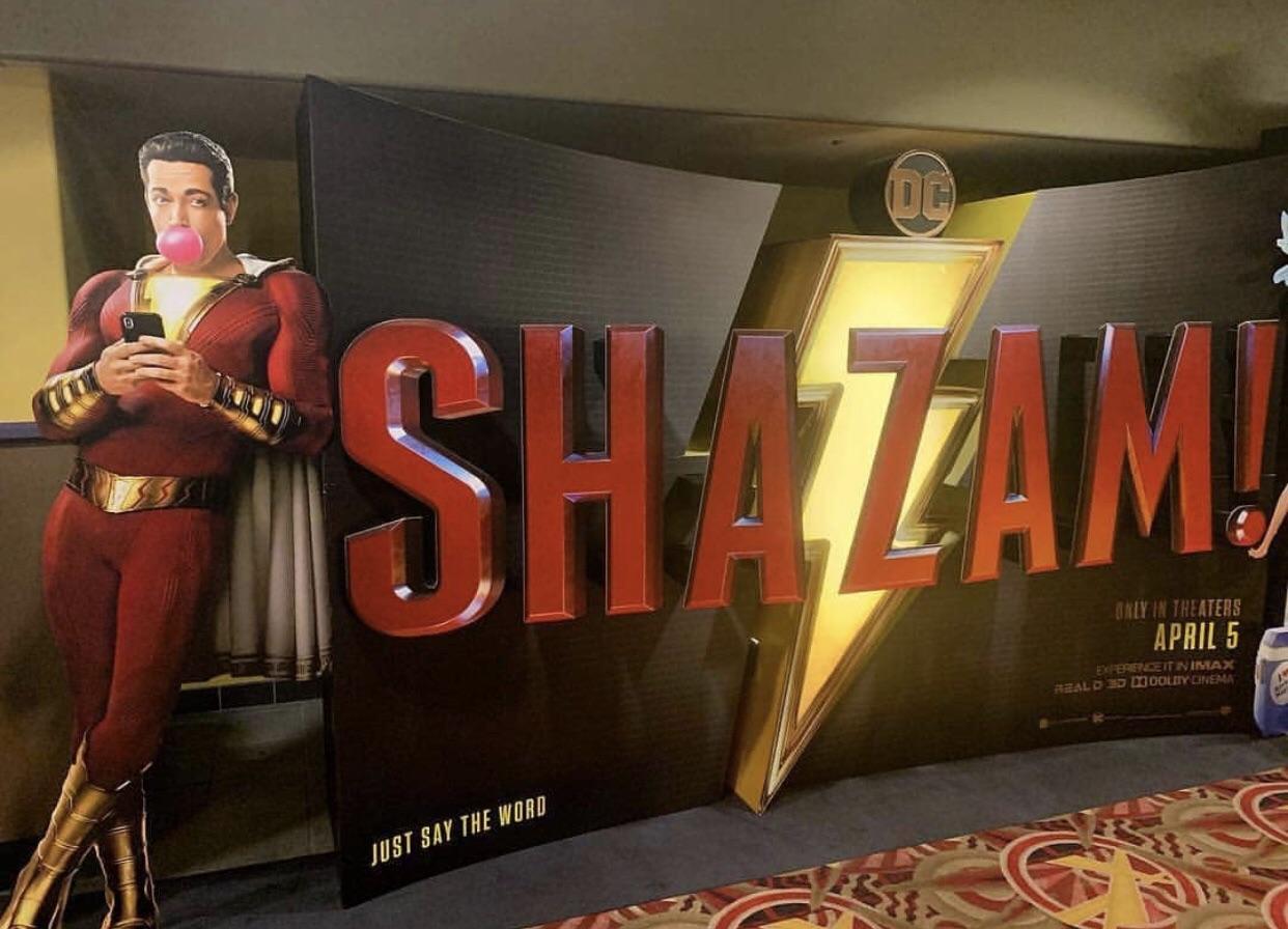 Shazam! Herói masca chiclete e usa celular em estande do filme