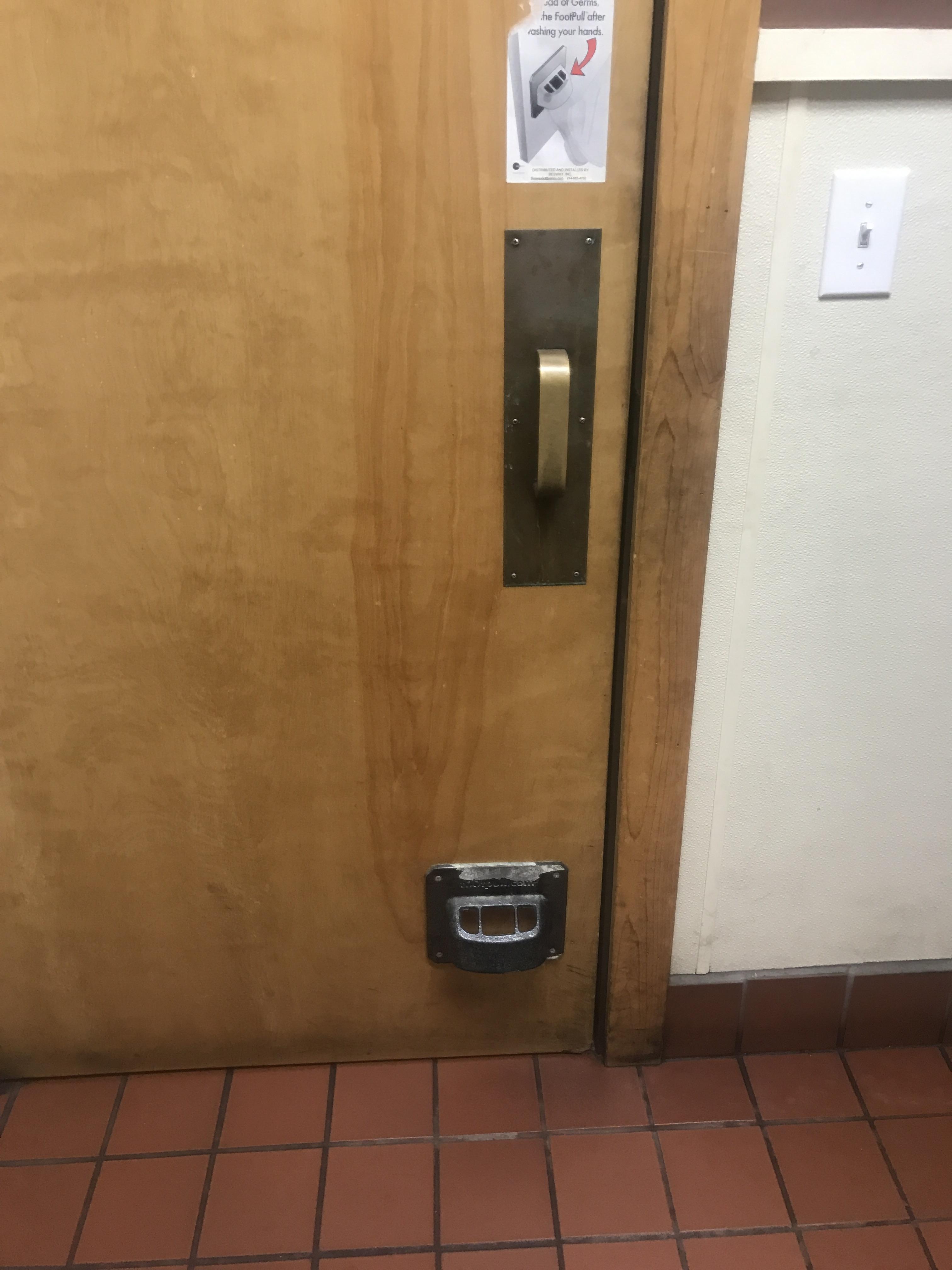 This bathroom door has a foot handle to prevent the spread of germs r