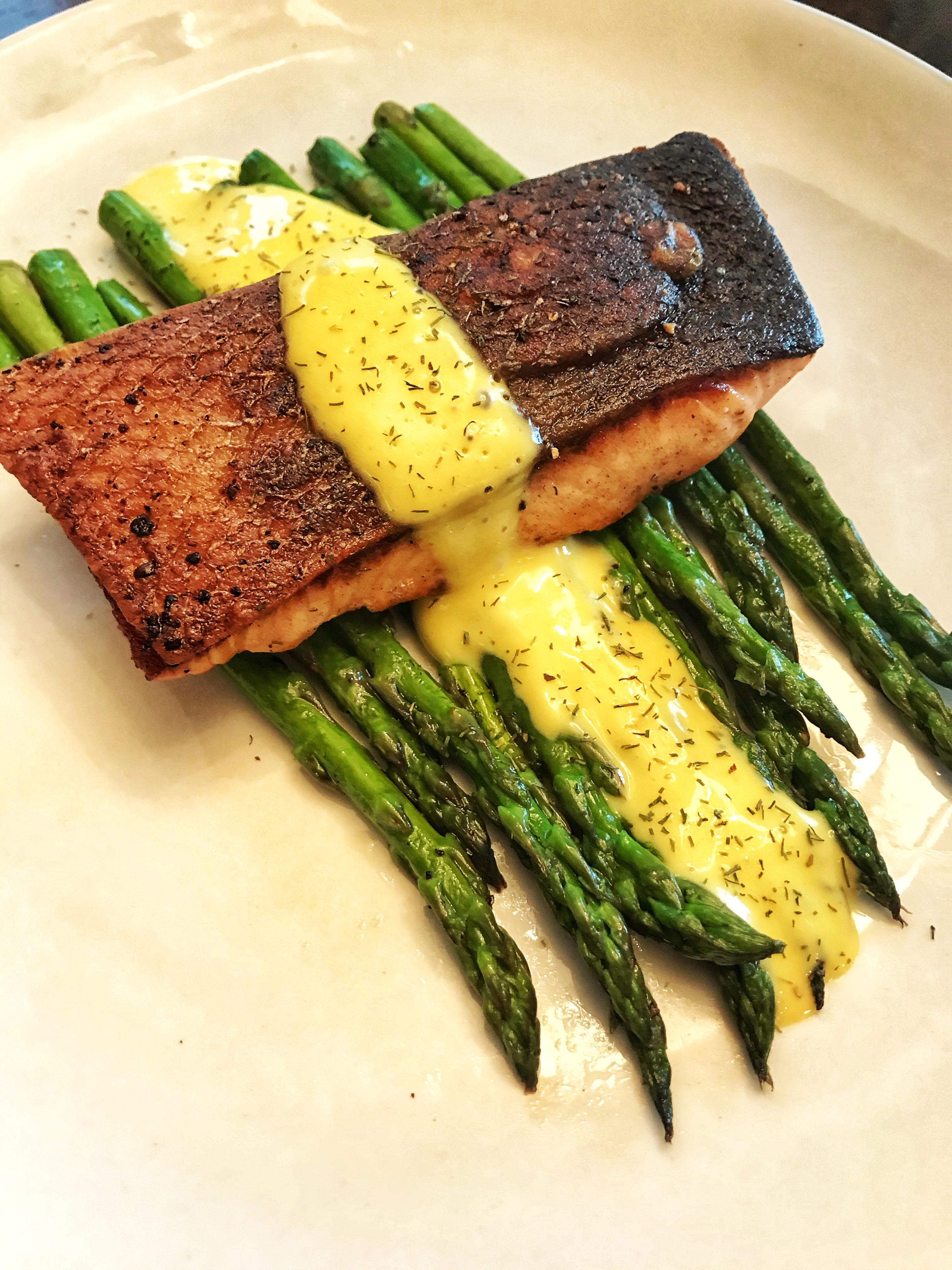 Homemade pan seared butter basted crispy skin salmon over asparagus with hollandaise and dill