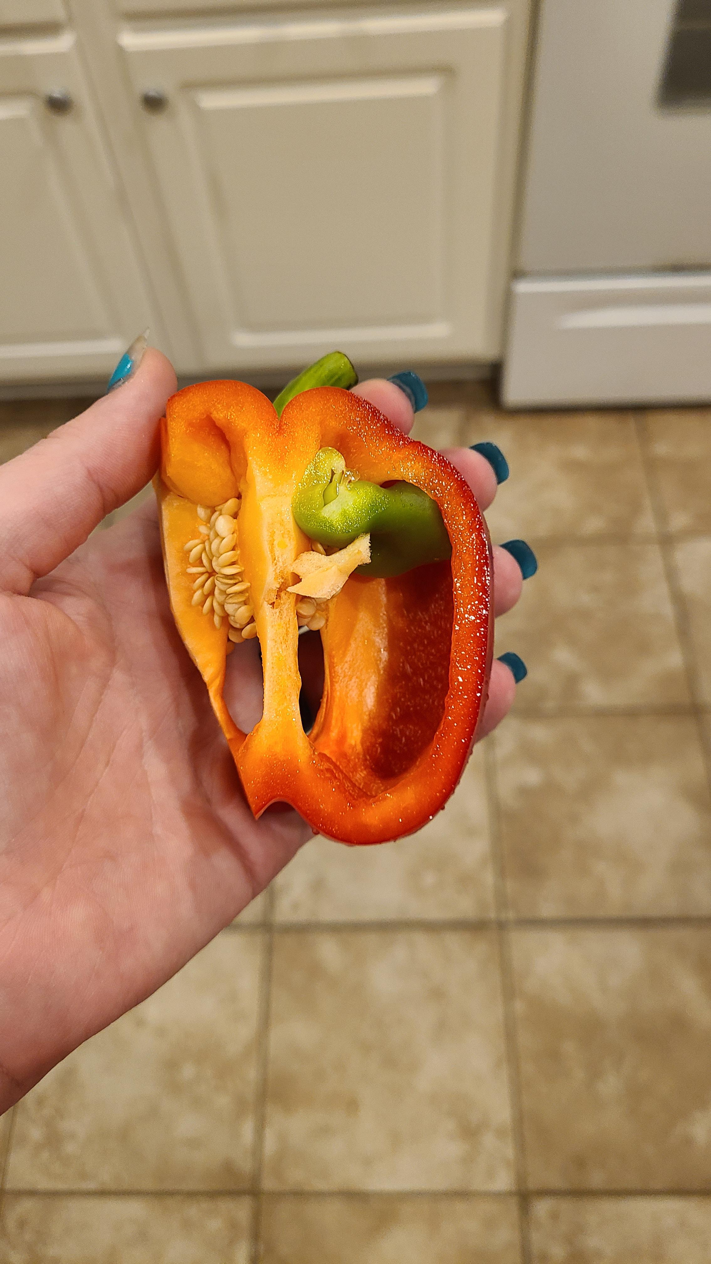 A green bell pepper is growing inside my red bell pepper