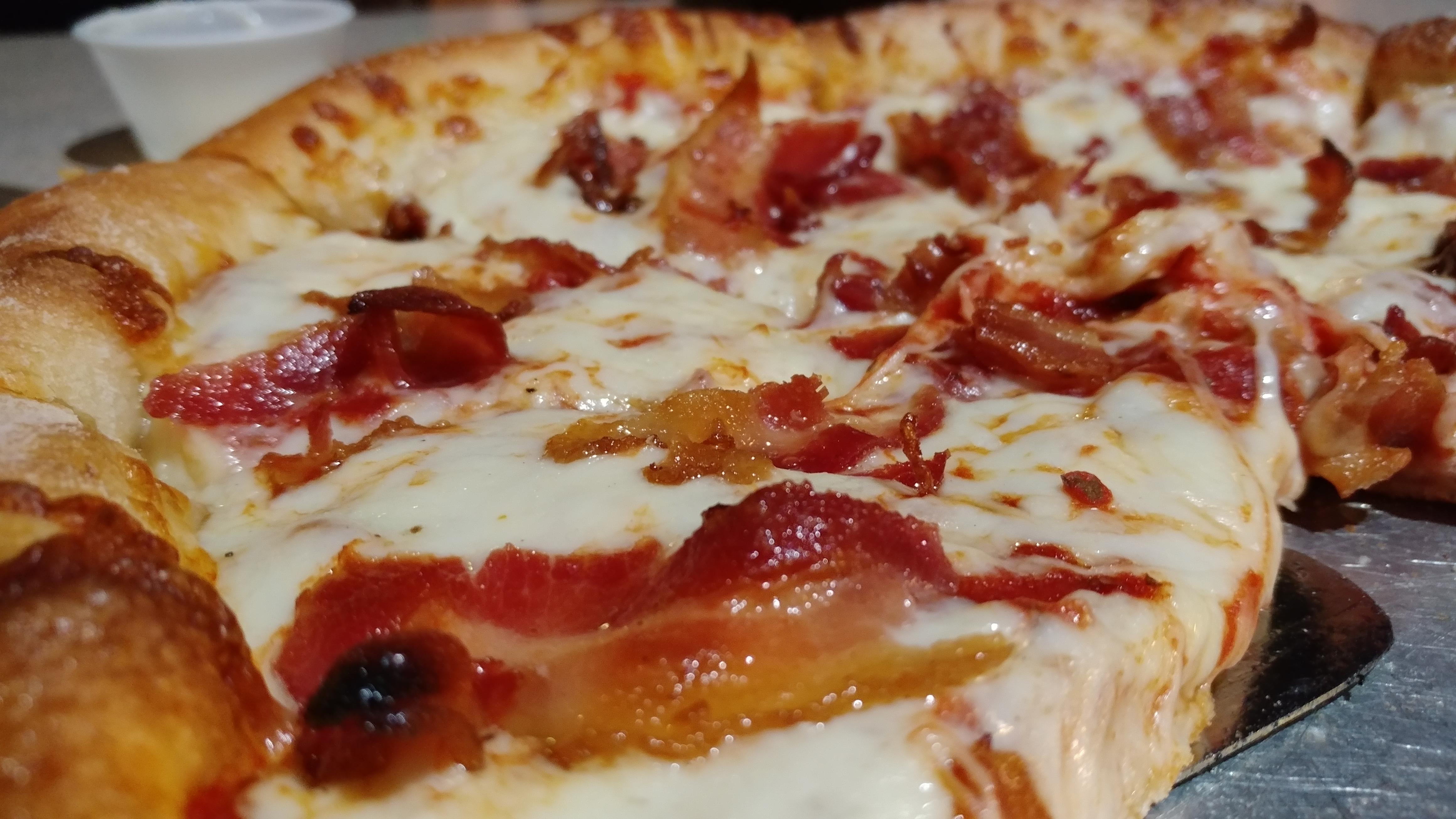 The local bar & grill uses full strips of bacon on their pizza