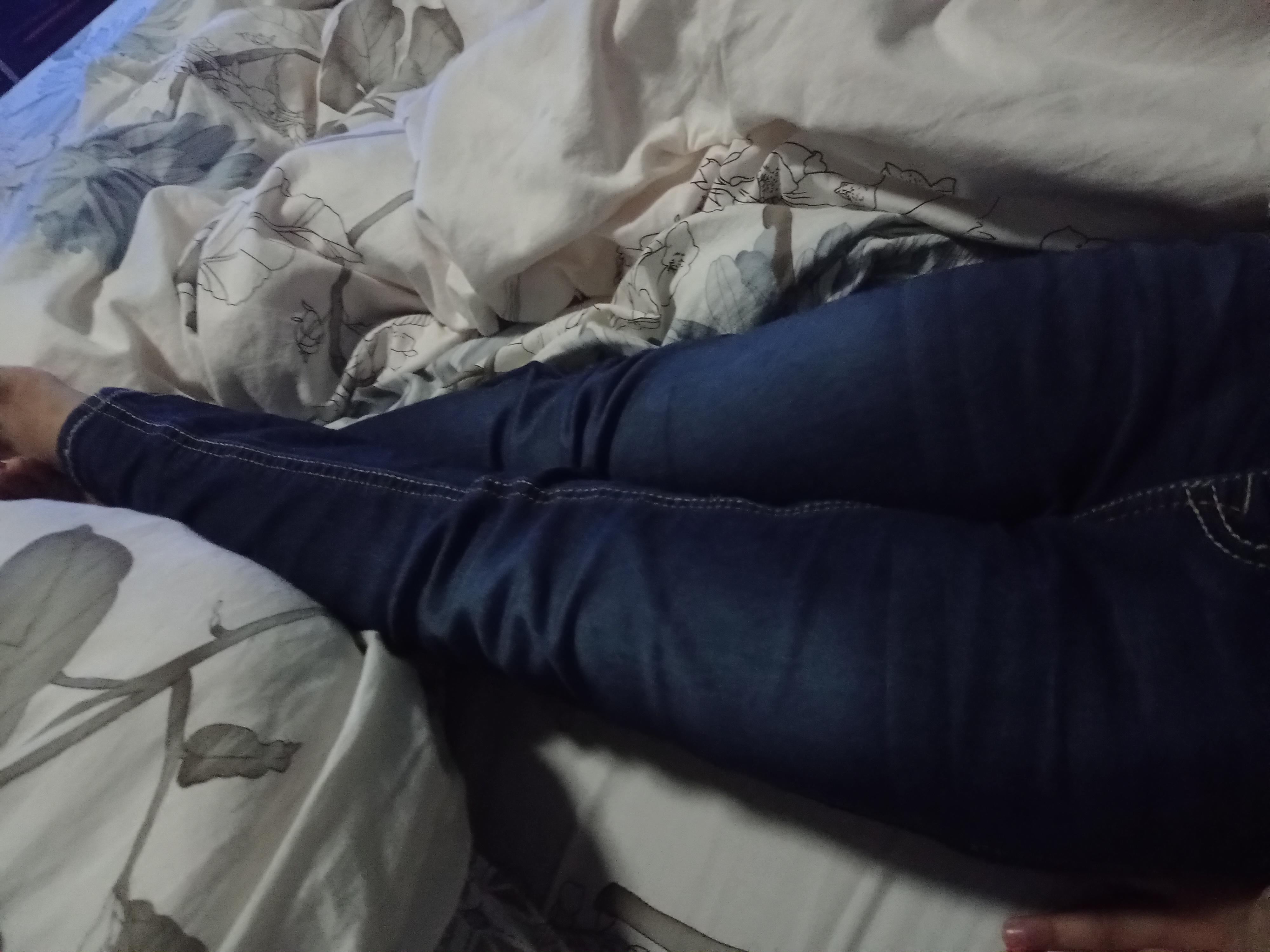 My little sister is wearing jeans, on bed, at night time, indoors. r