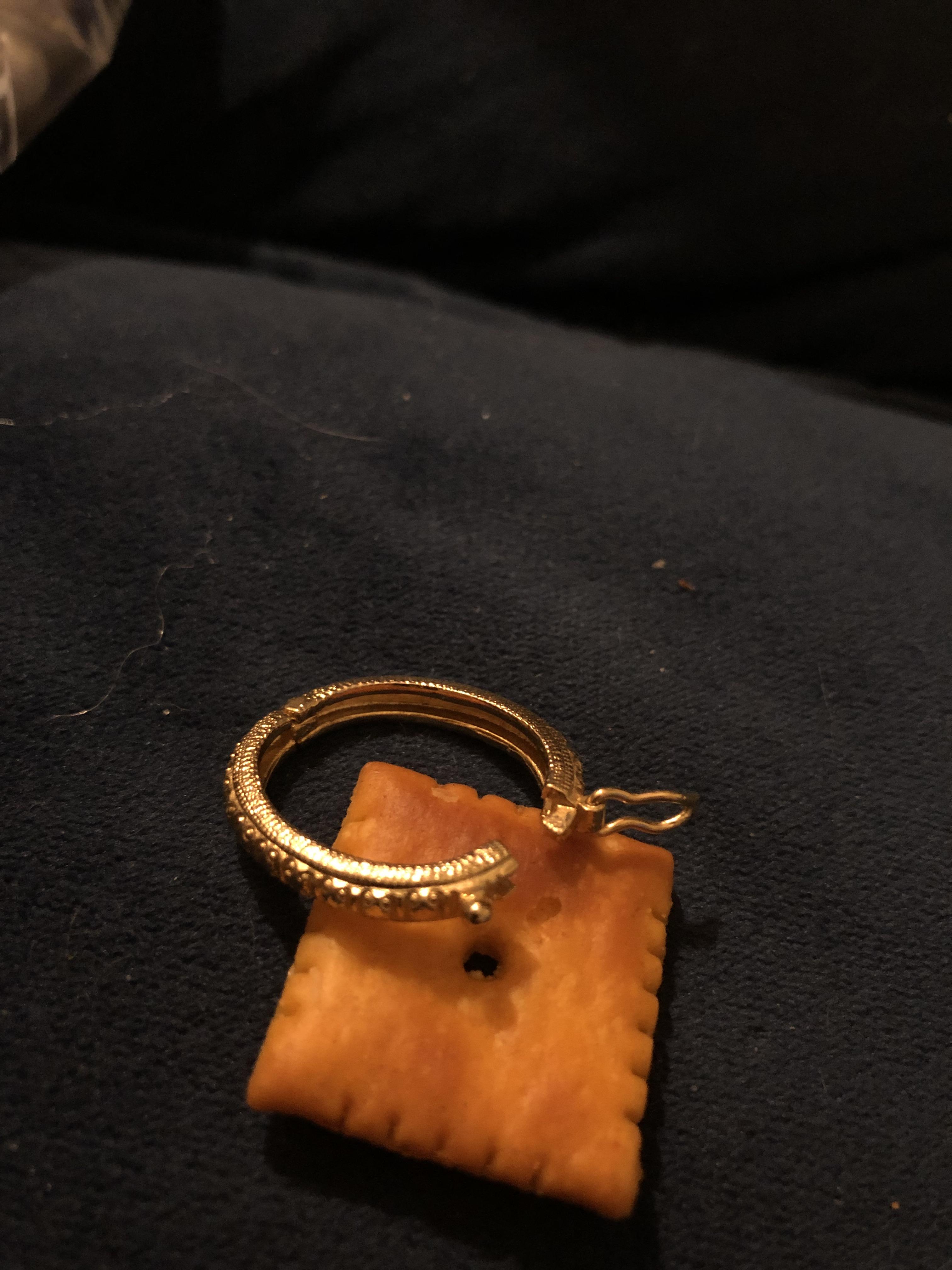 Small oval shaped gold jewelry with clasp, cheezit for scale. More