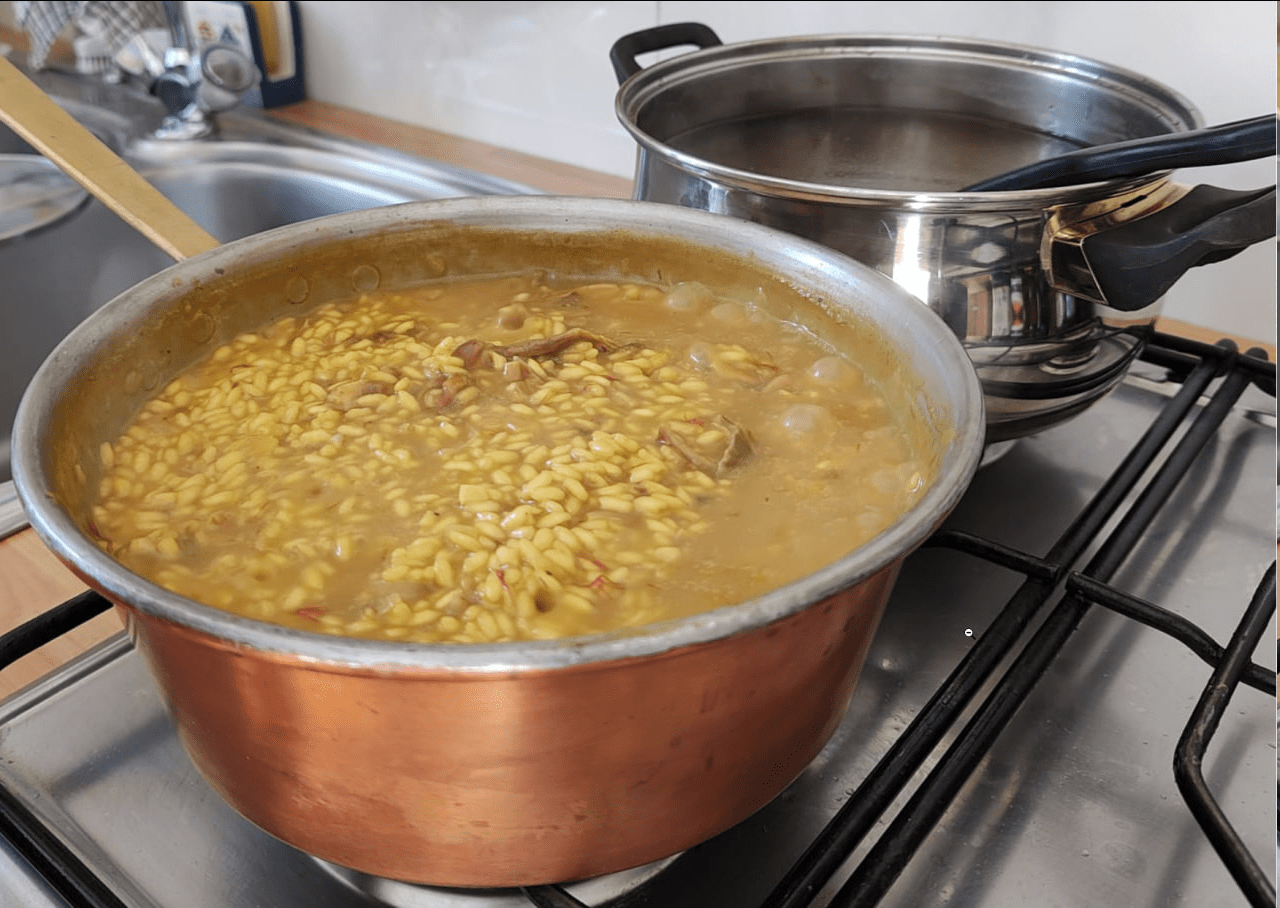 Risotto giallo con funghi porcini secchi; pentola di brodo fatto in