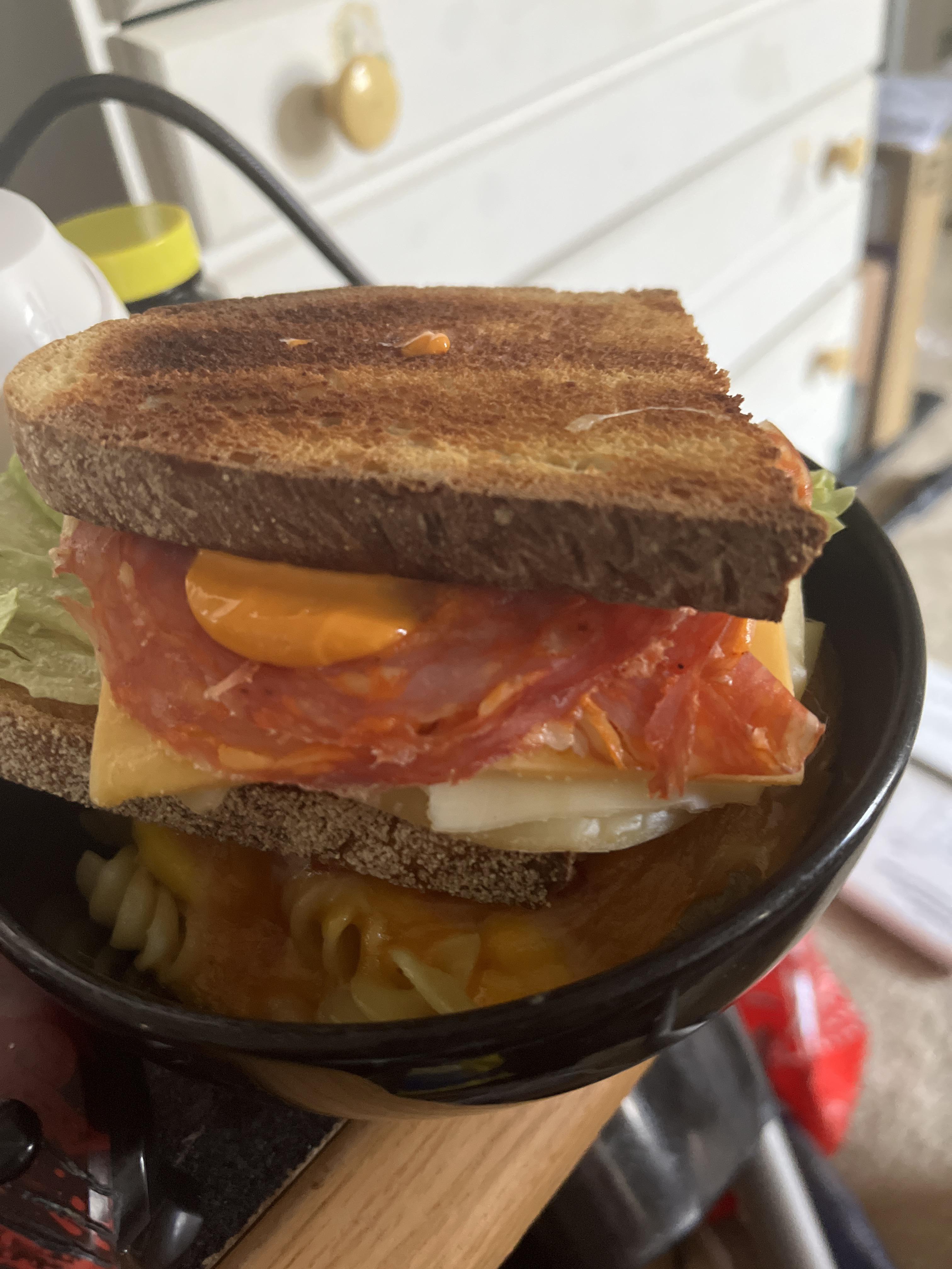 Spicy salami and cheese sandwich with provolone cheese, cheddar cheese, iceberg lettuce with red
