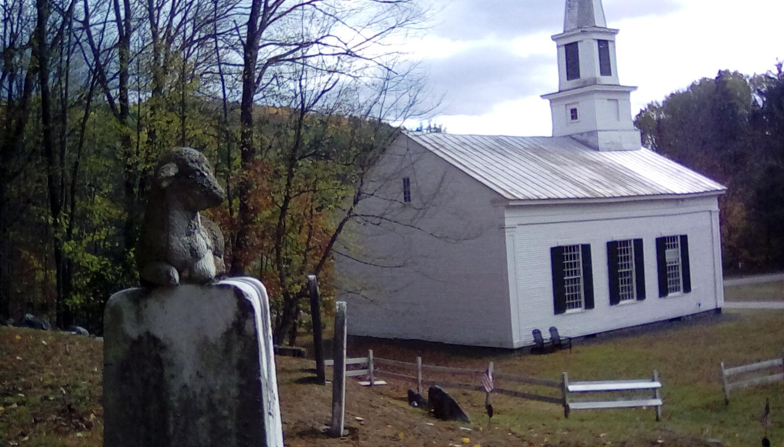 A lamb overlooking the church at a quiet country graveyard, West