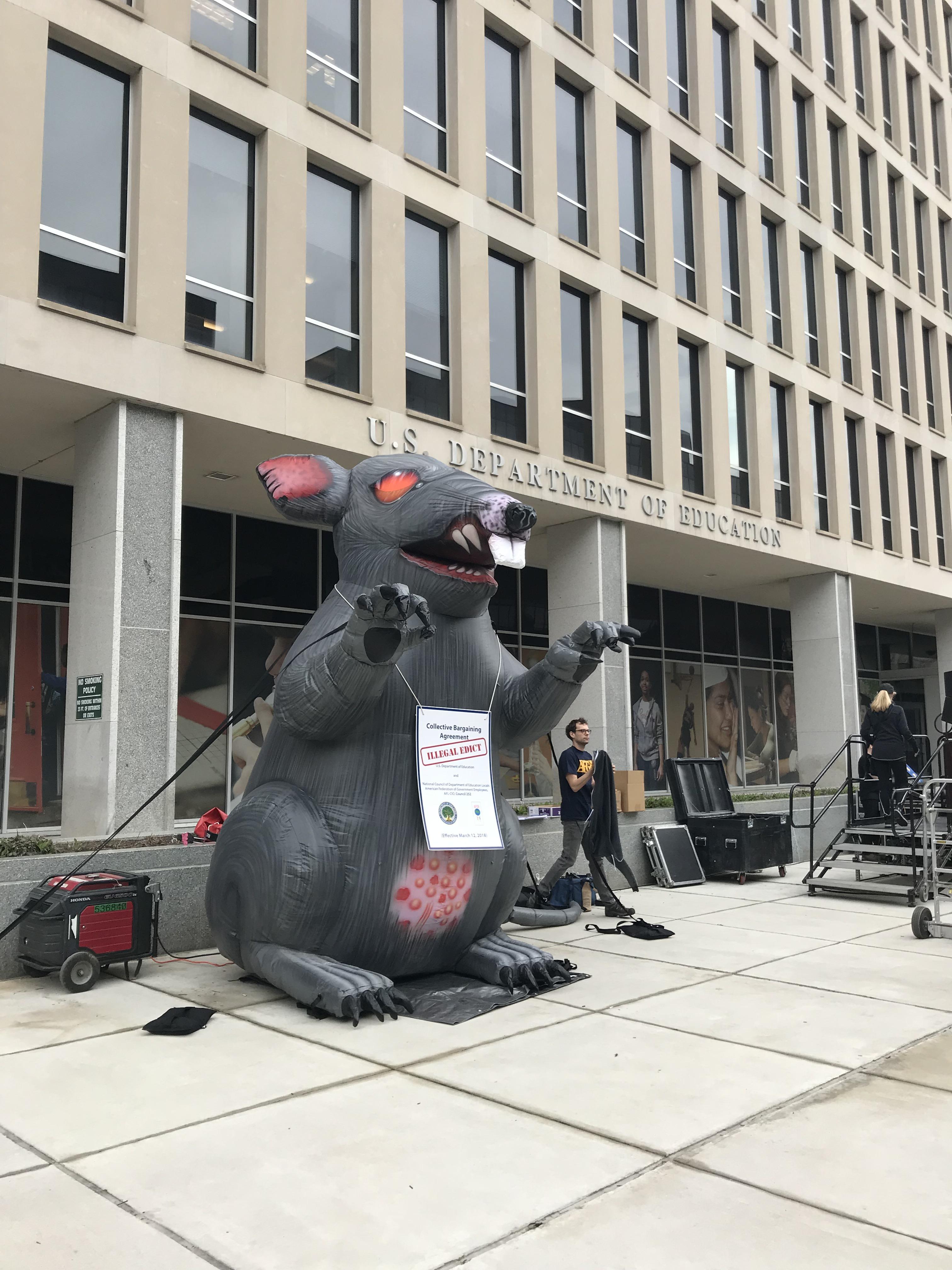 A giant inflatable rat is currently set up in front of the US Dept. of