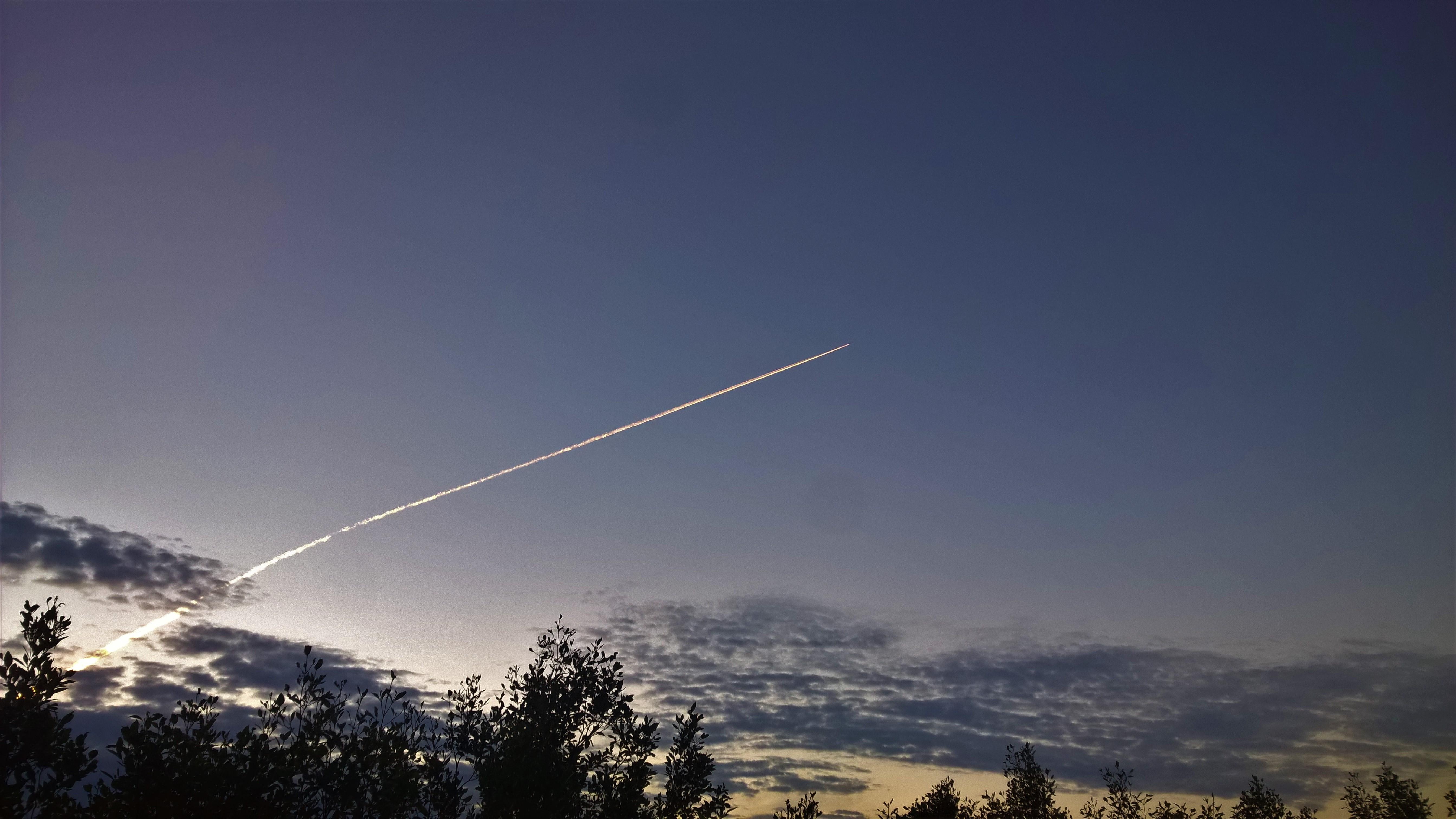 Jet condensation trail reflecting dawn light from over the horizon this