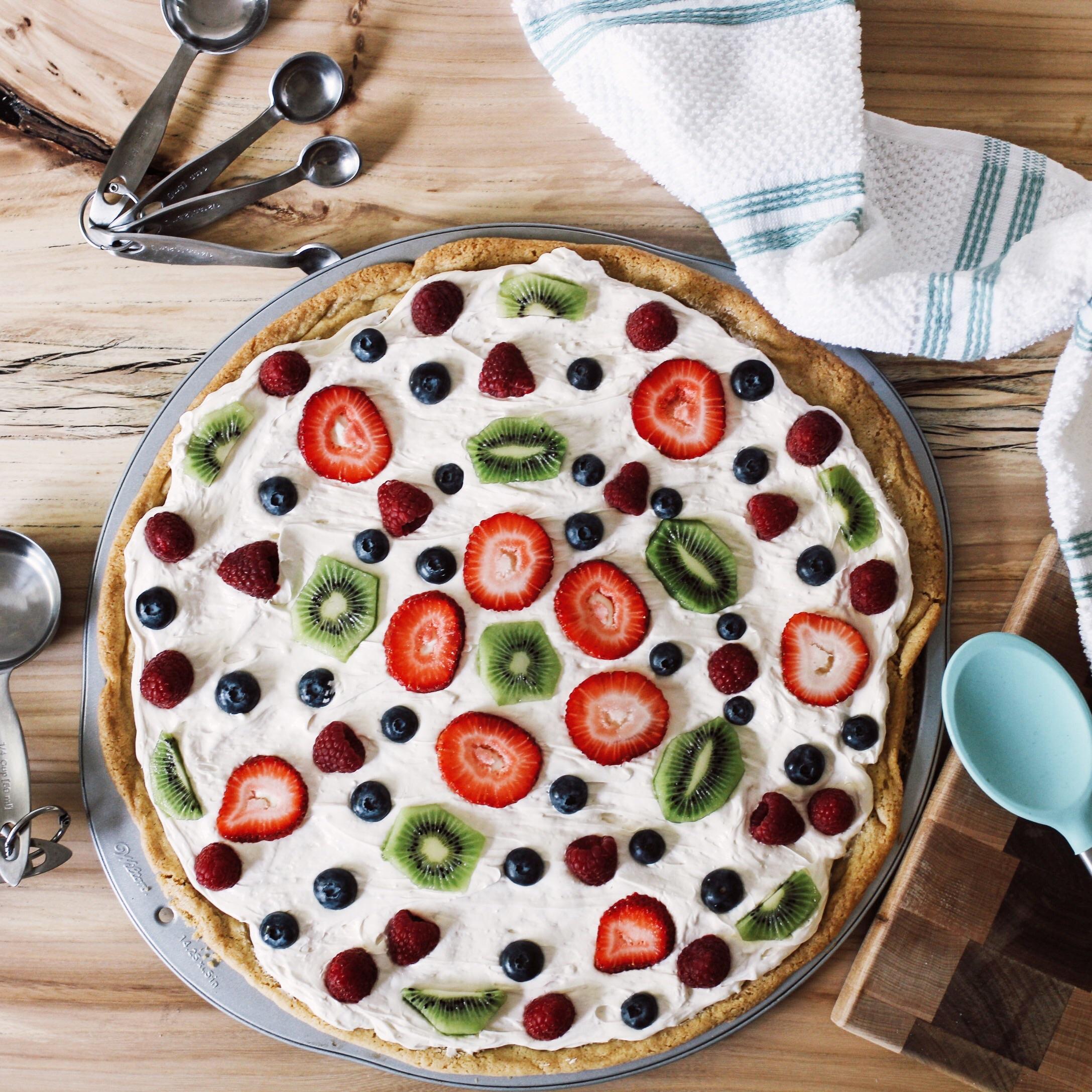 Fruit pizza with sugar cookie dough, whipped cream cheese sauce