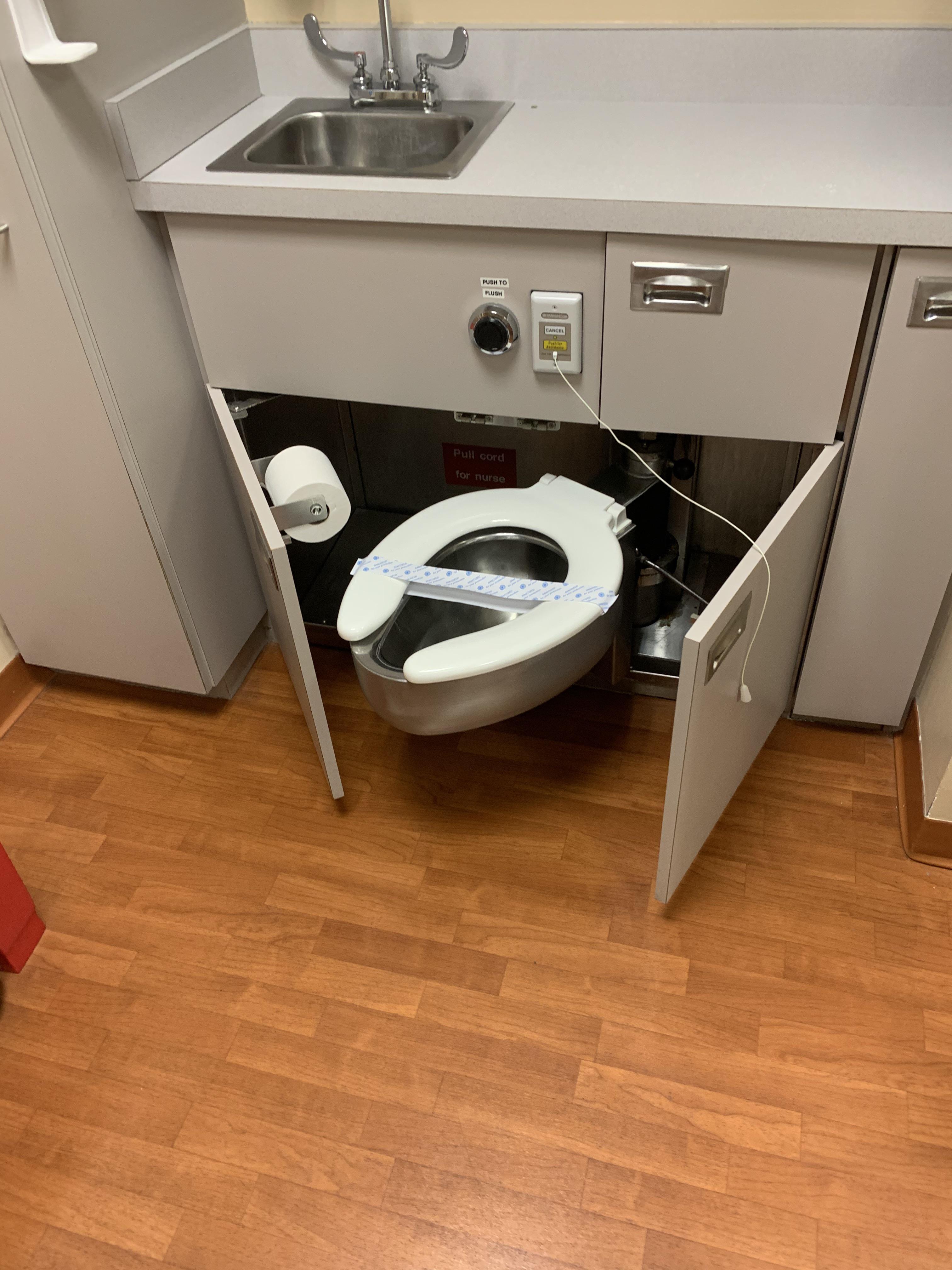This toilet pulls out from underneath a sink in the hospital room. r