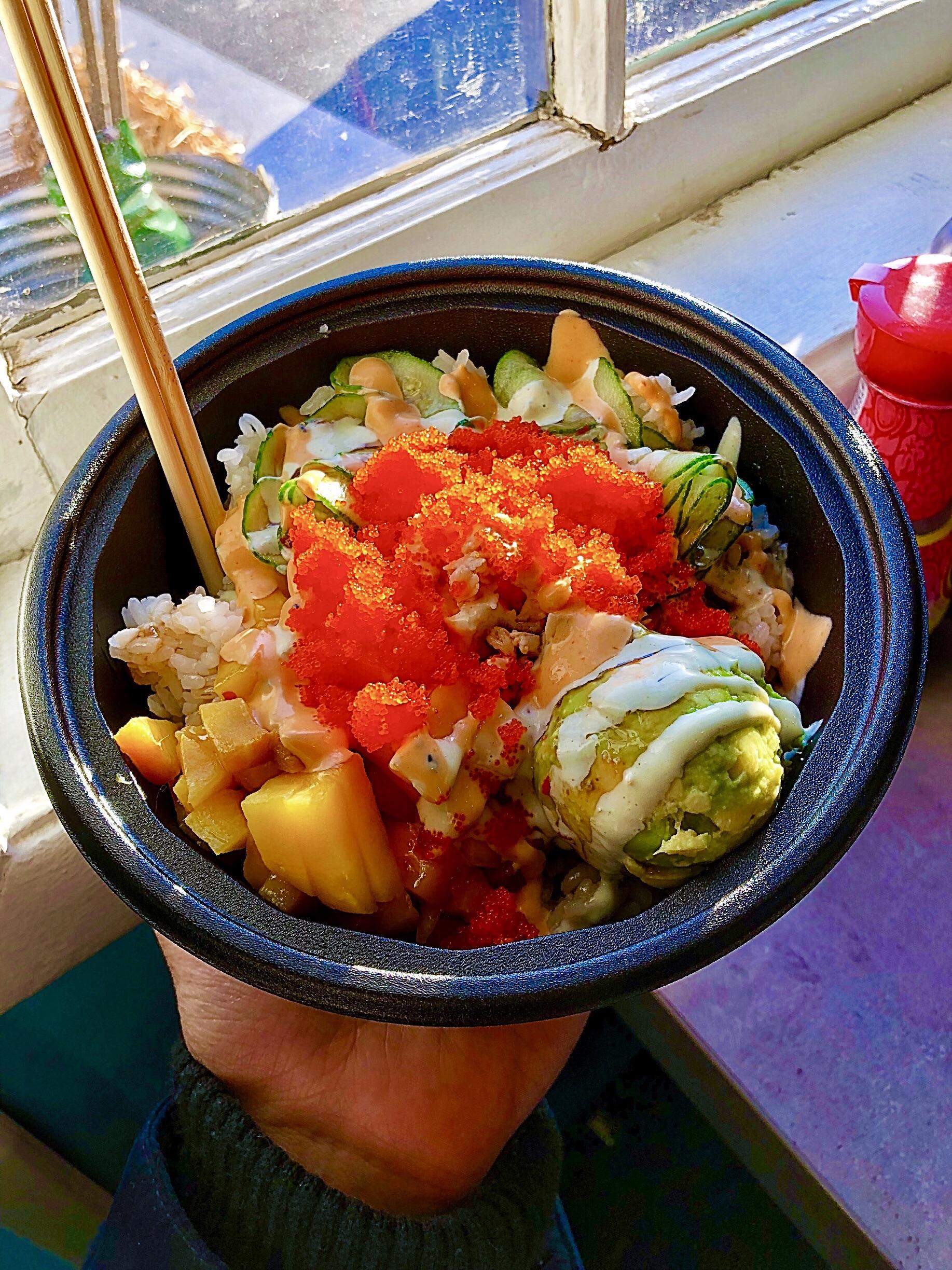 Crab Poke bowl topped with mango, roe, and cucumber, drizzled with