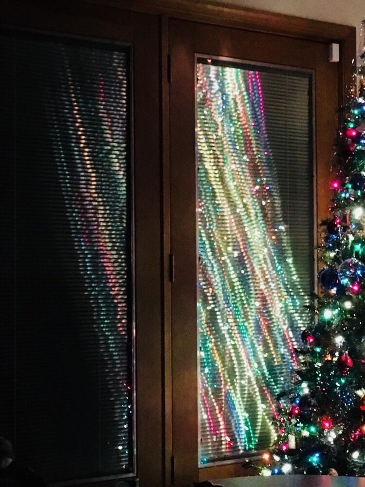 Christmas tree lights reflecting on glass doors with blinds. r/pics