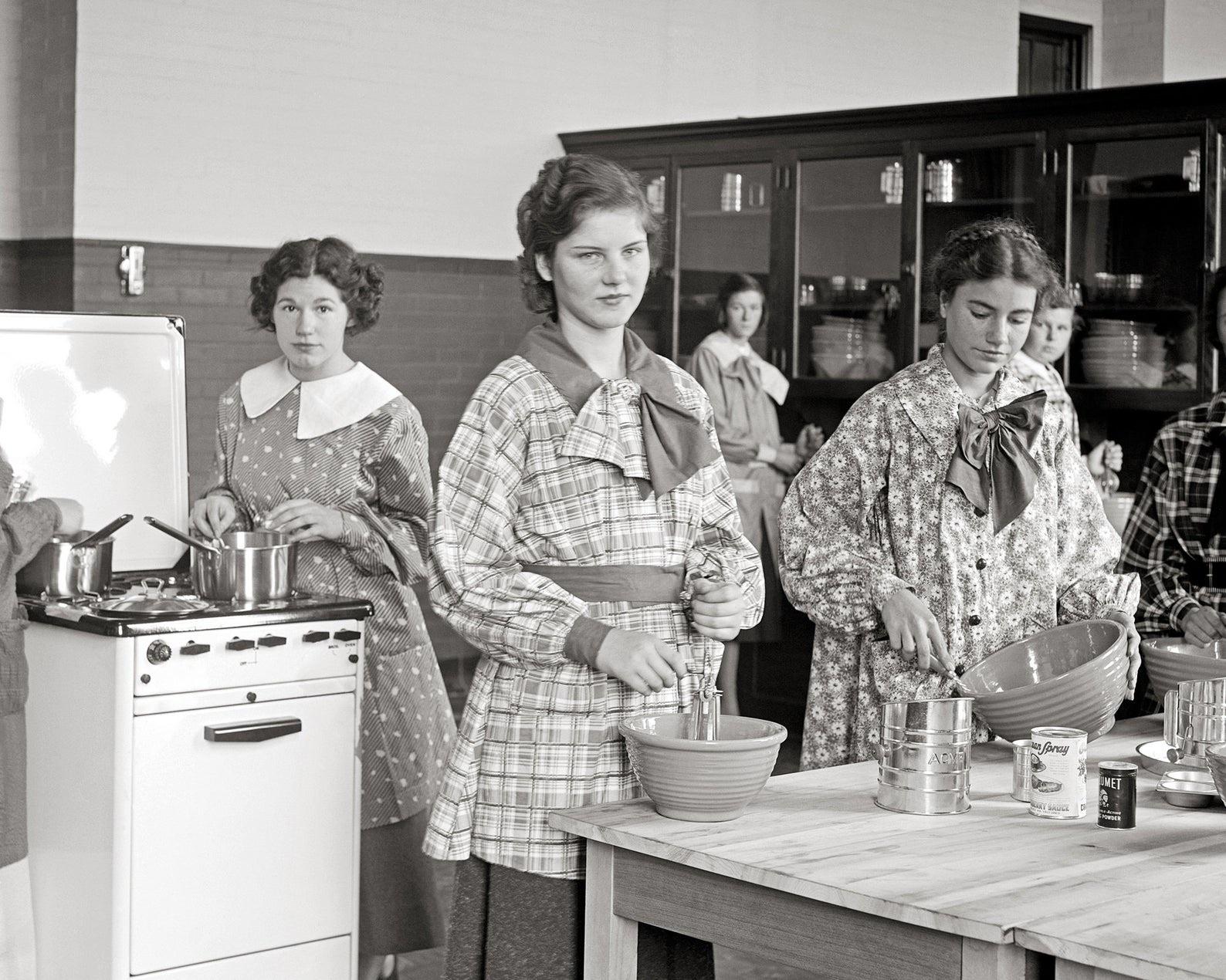 A group of girls cooking in a high school home economics class. Silver