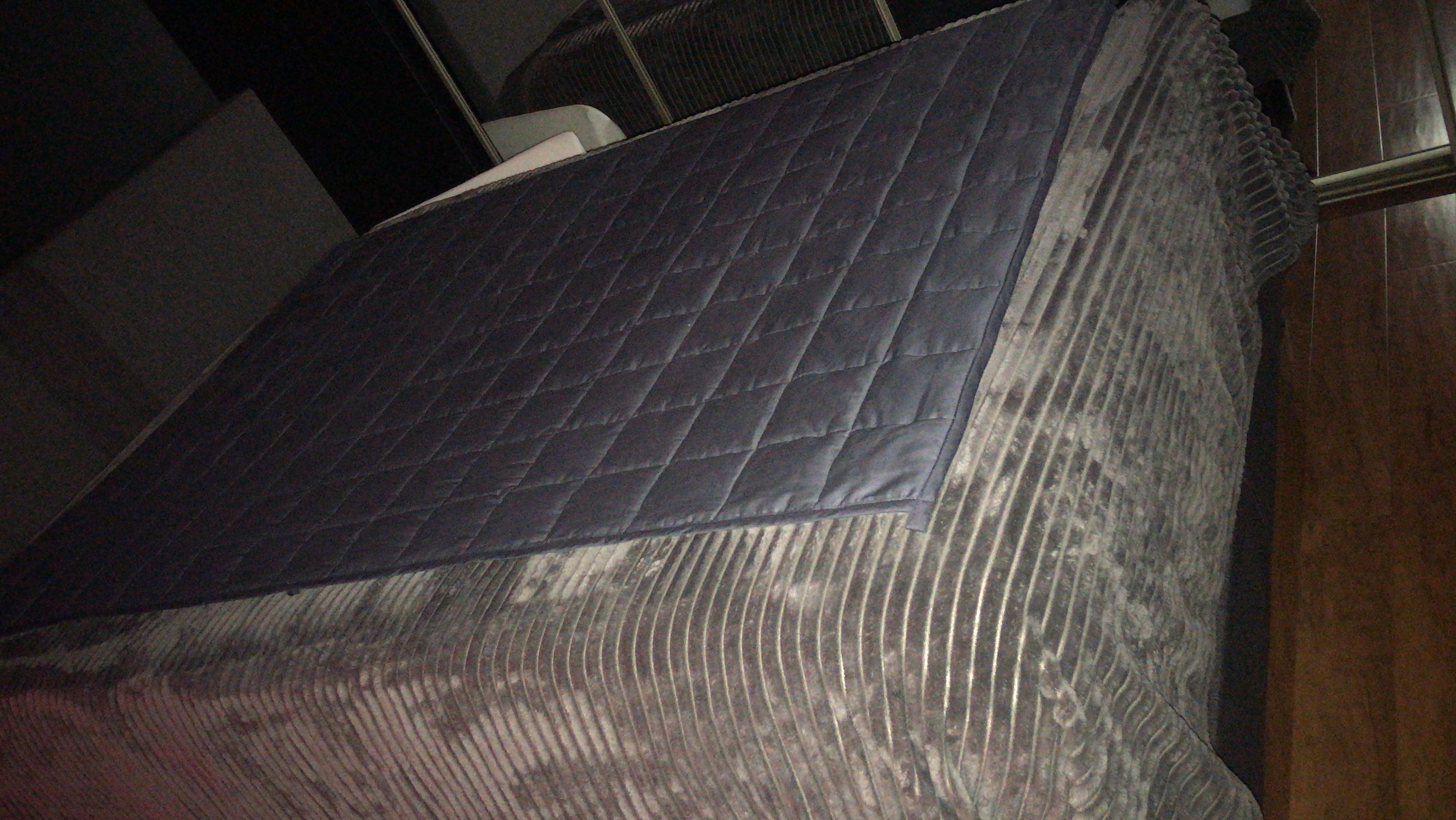 Weighted blanket on freshly made bed awaiting clean comforter from the