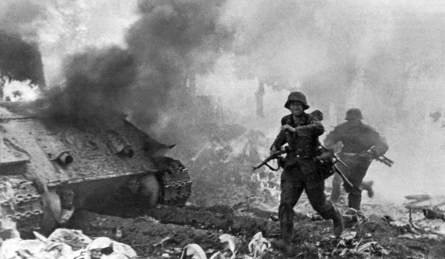 Grenadiers of the SS "Totenkopf" run past a burning tank in Warsaw