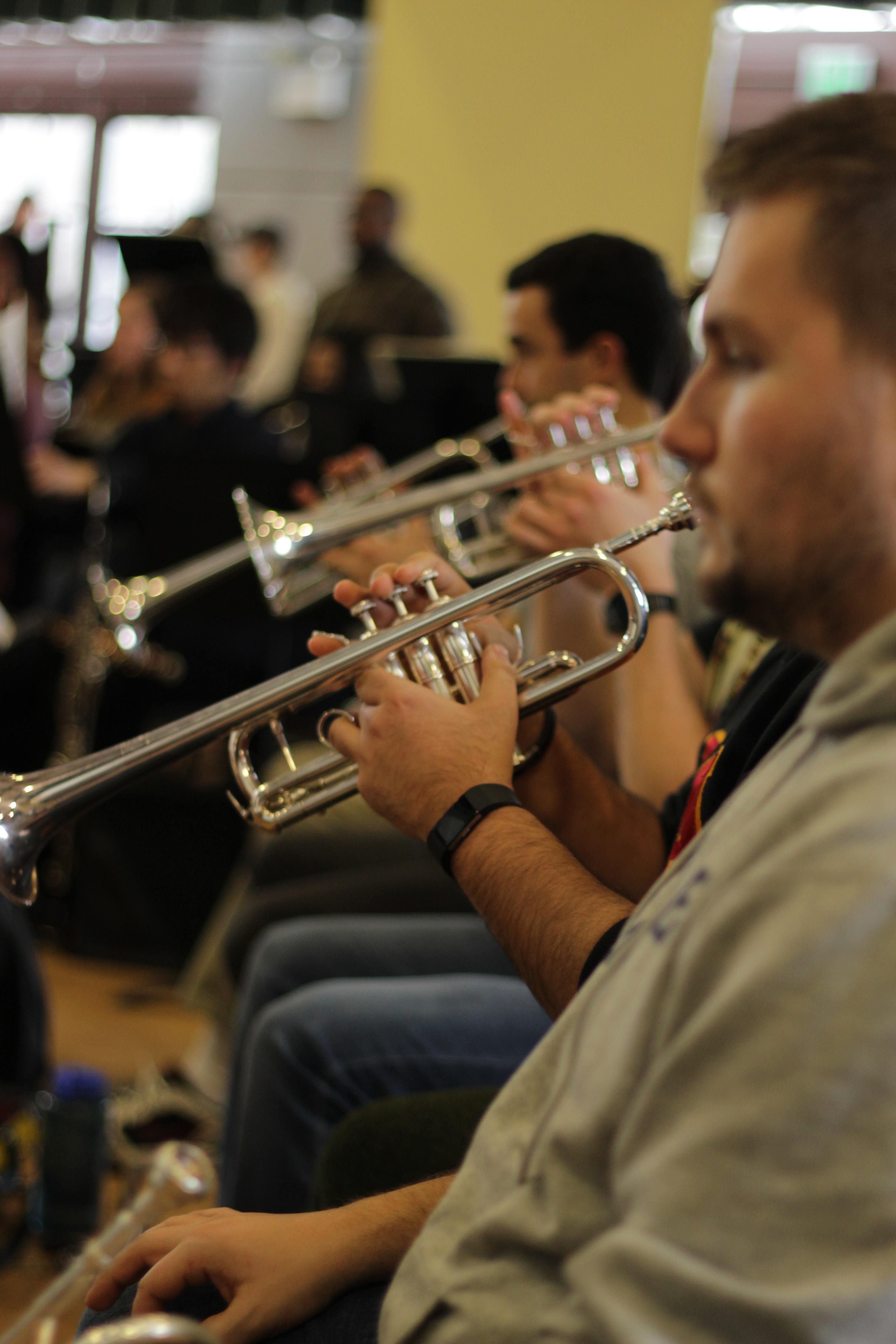 The second trumpet player's instrument is perfectly aligned with the