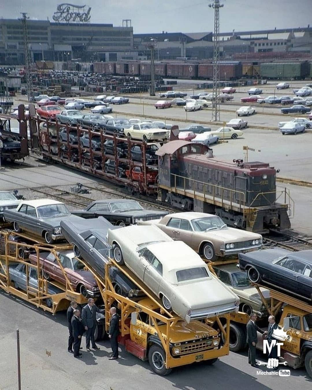 Several Mustangs loaded on a train car outside of the Dearborn Assembly