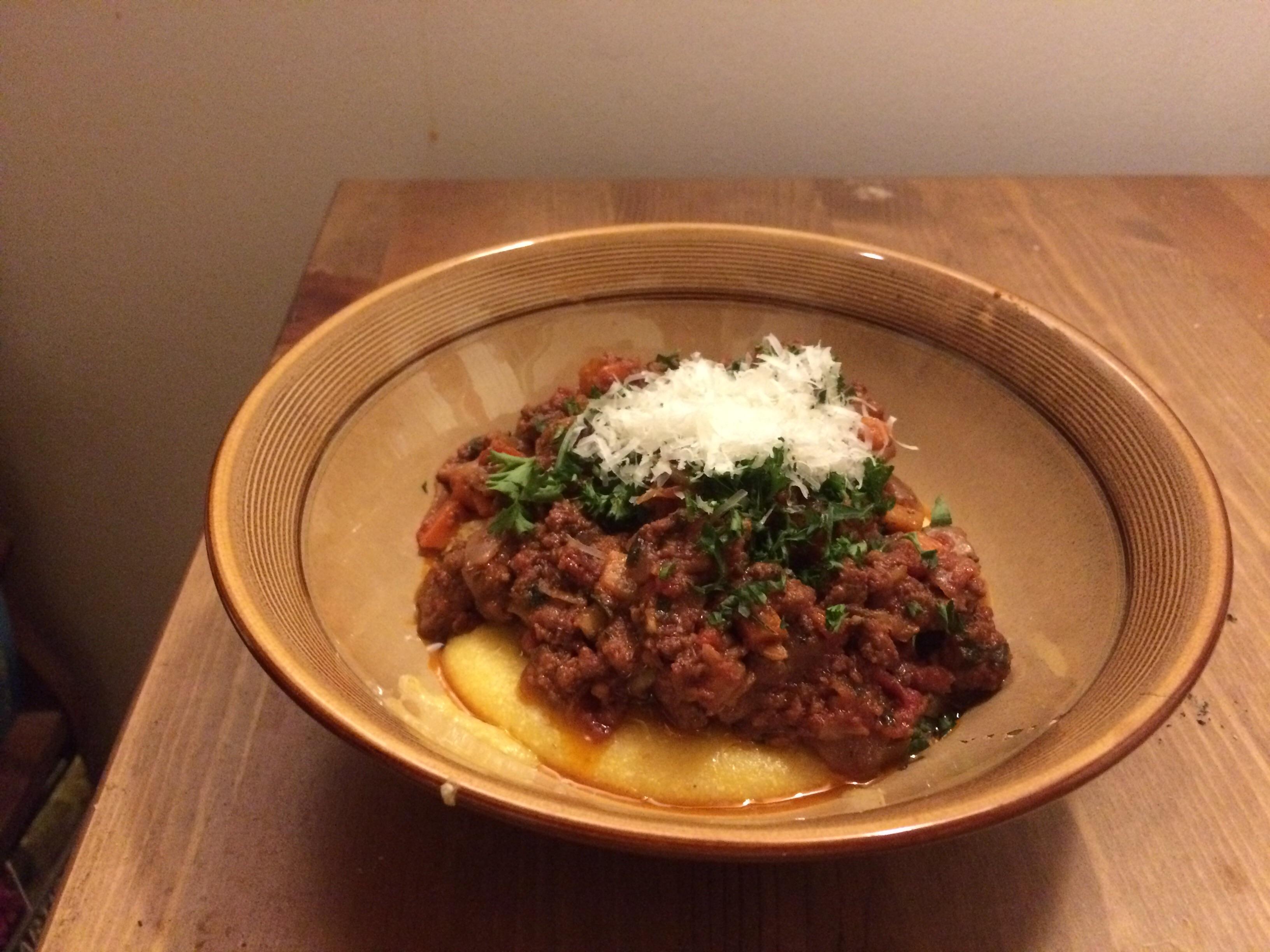 Lamb Bolognese over polenta, topped with parsley and Parmesan r