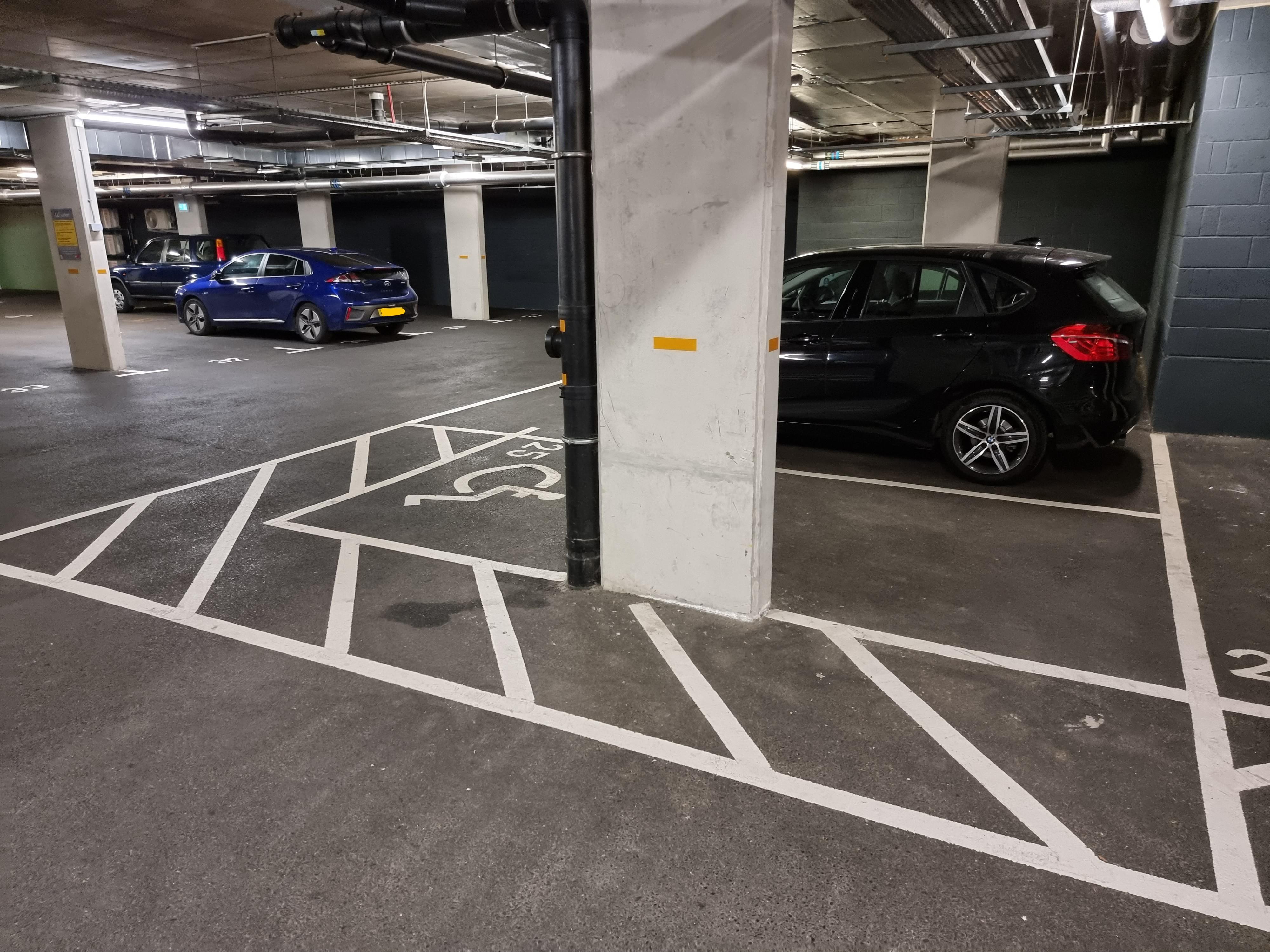 A Disabled parking space where a giant concrete pillar makes it more