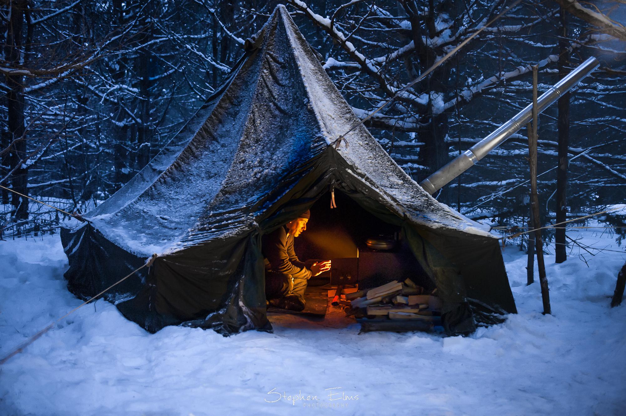 Warming up by the wood stove in my hot tent in Algonquin Park, Ontario
