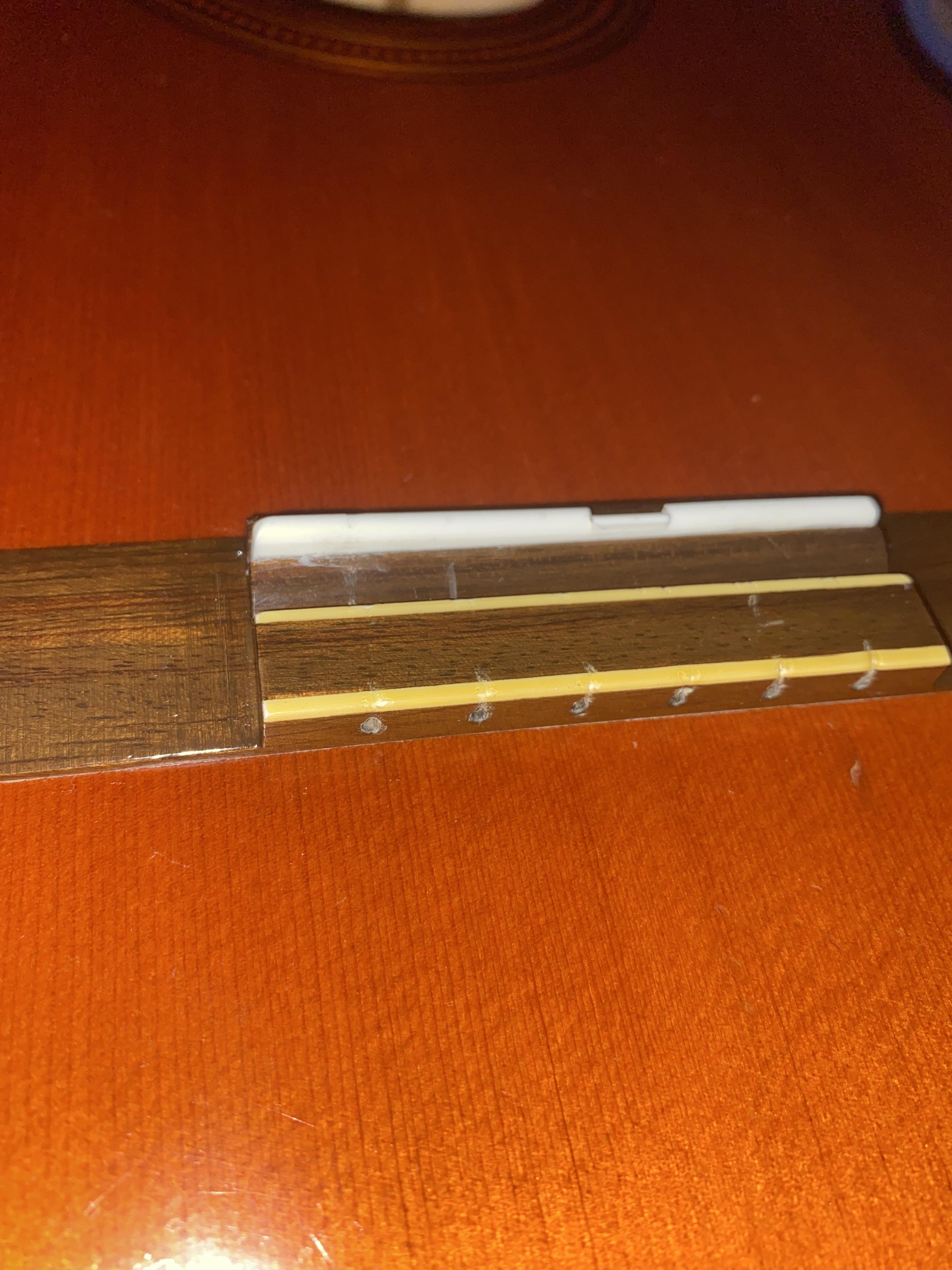 As you can see the low E string is higher on the bridge than the high E