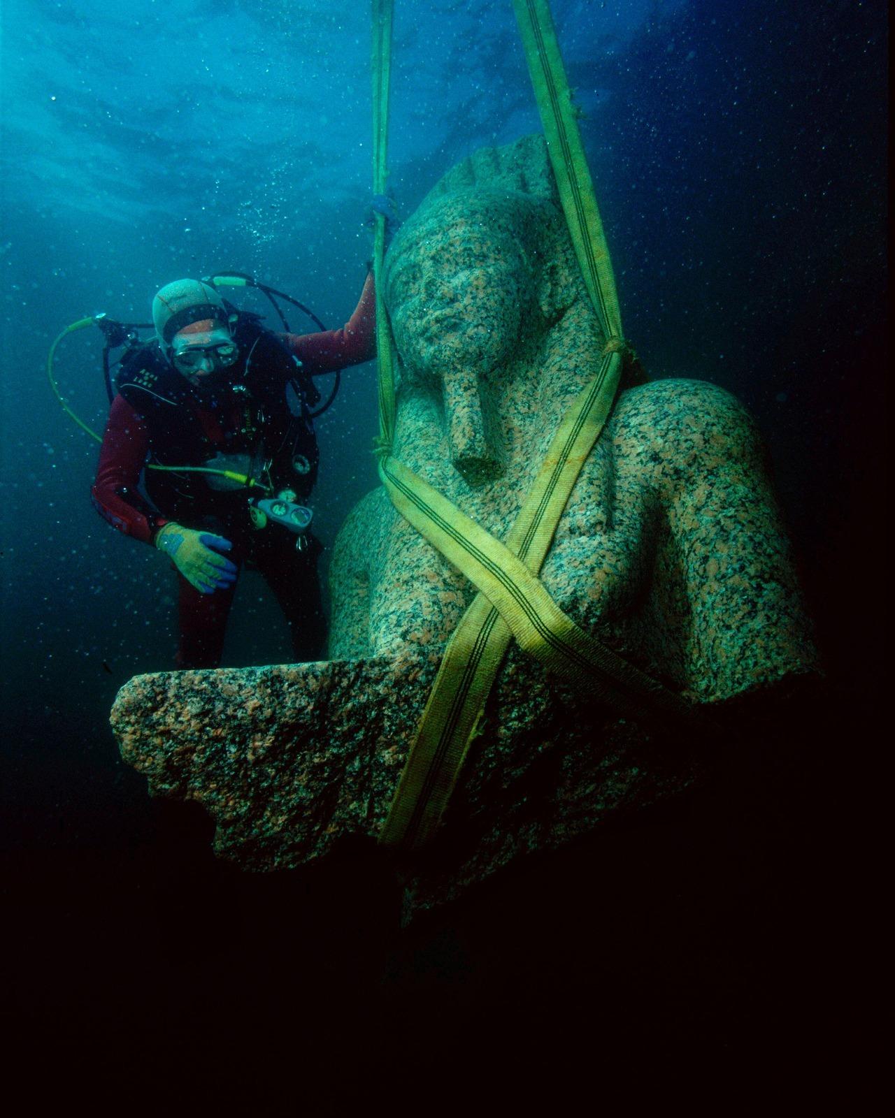 Diver excavates a large statue from the sunken city of Thonis