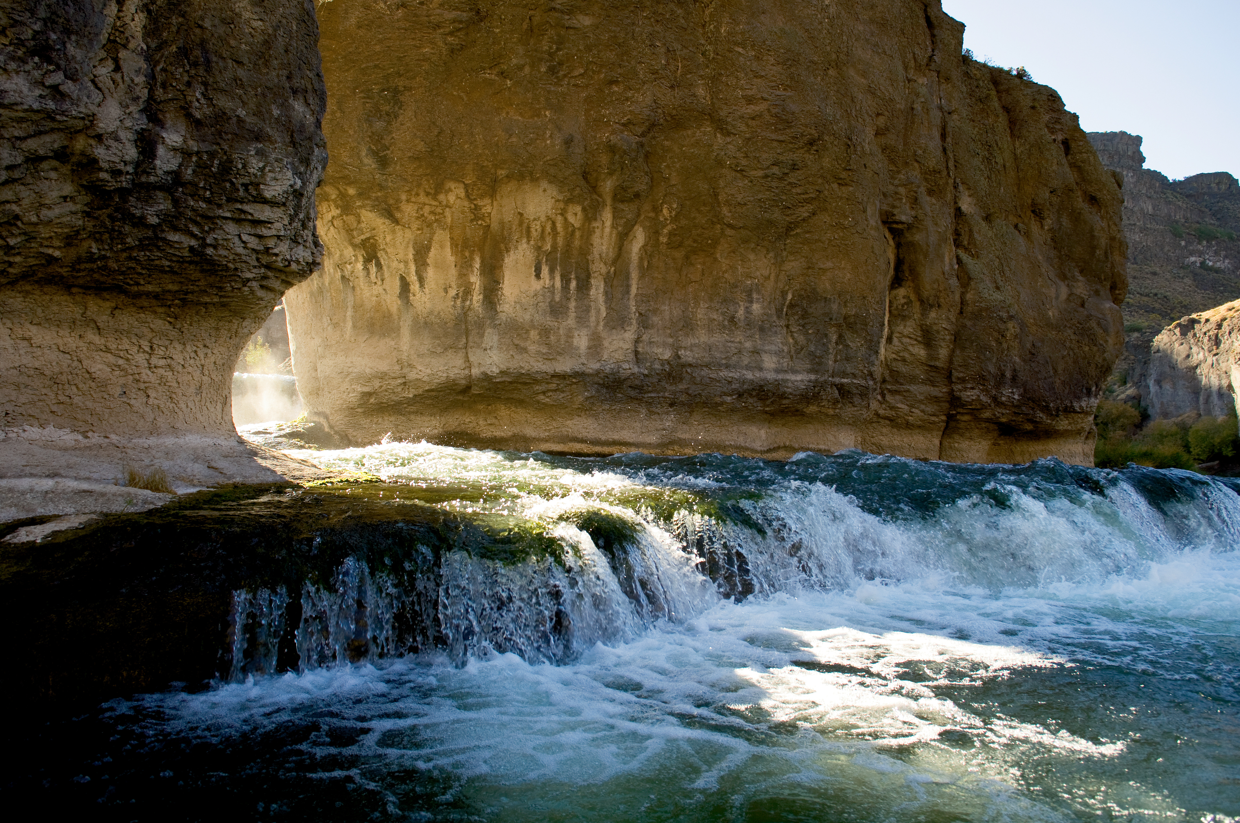 Water flows through the rock formations at Pillar Falls as the sun rises above the Snake River