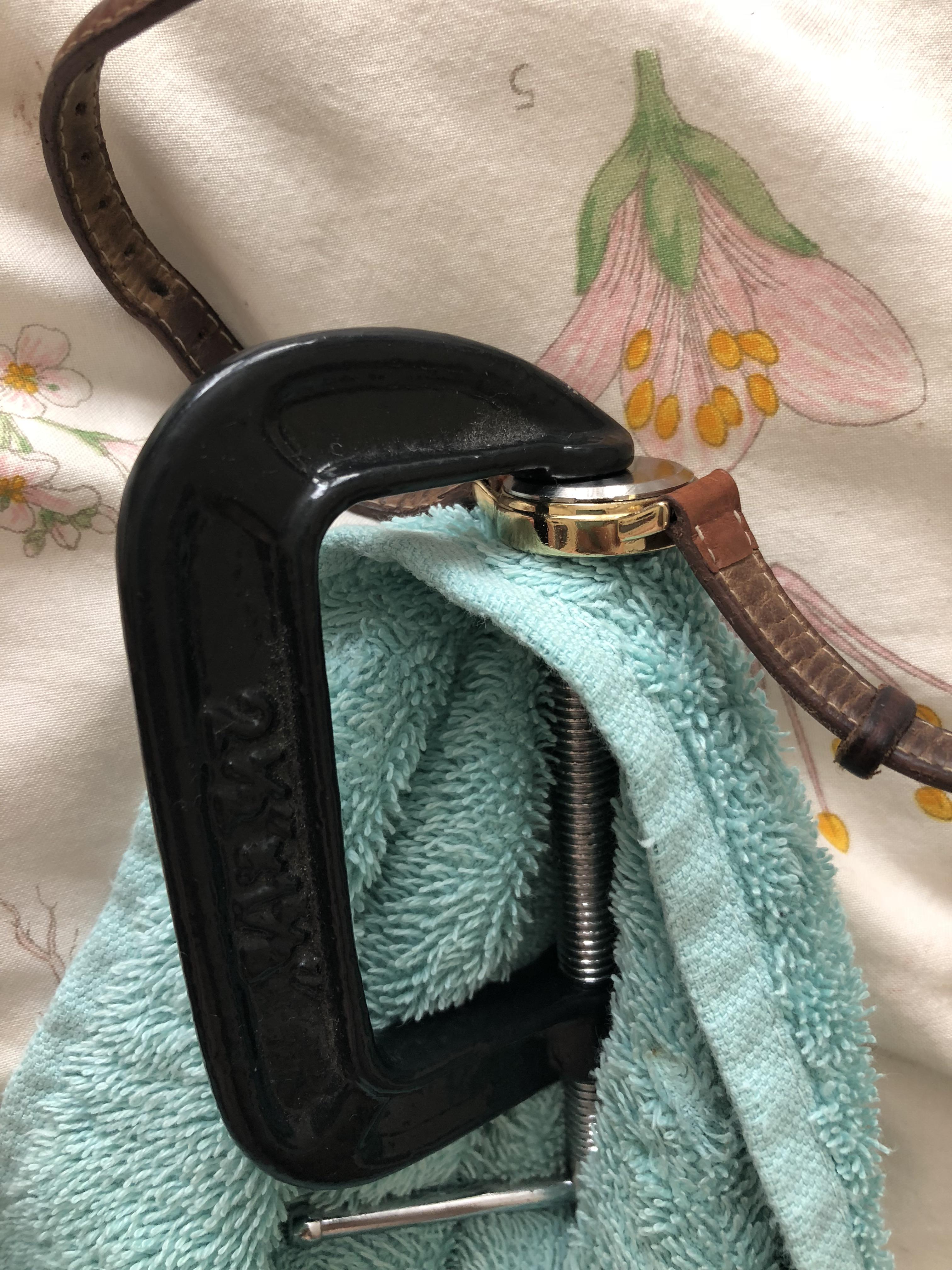 Watch back won’t pop on? Use a towel and a clamp to press it back on