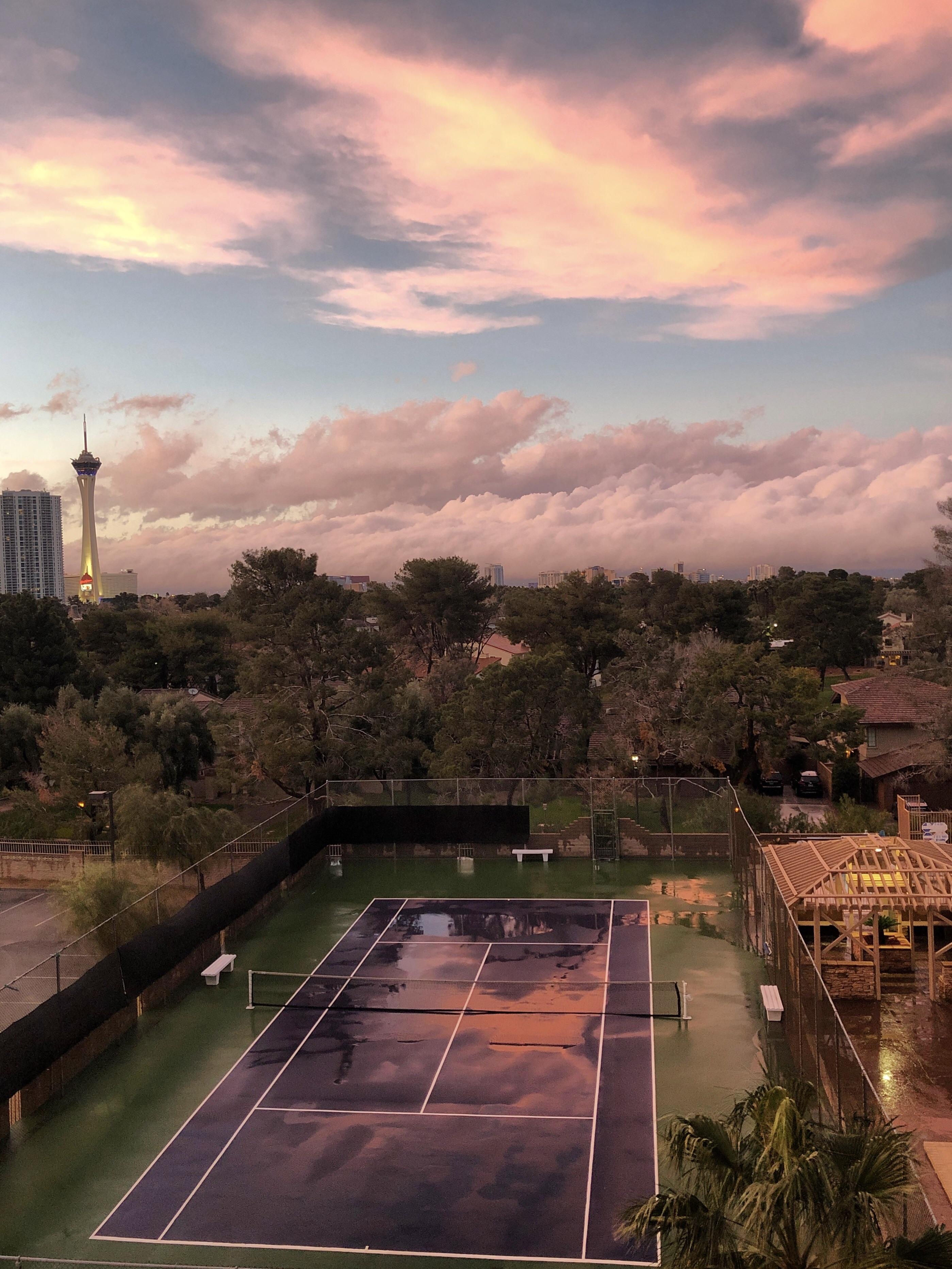 ITAP of pink clouds reflected in a tennis court after a