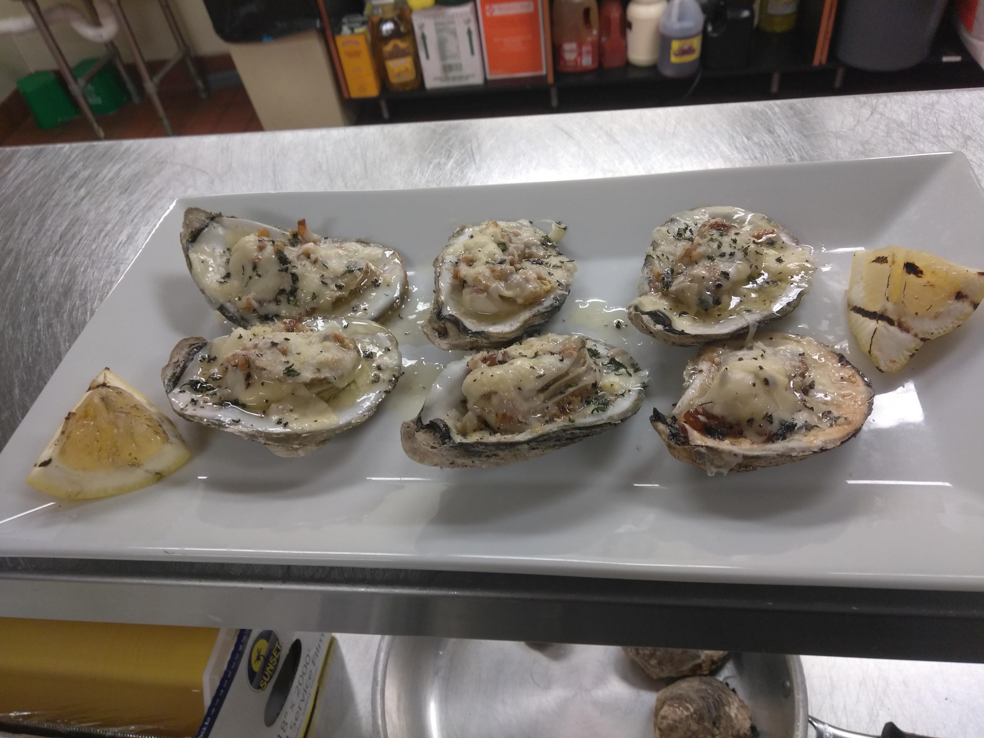 Charbroiled oysters with garlic butter herb sauce and toasted parmesan