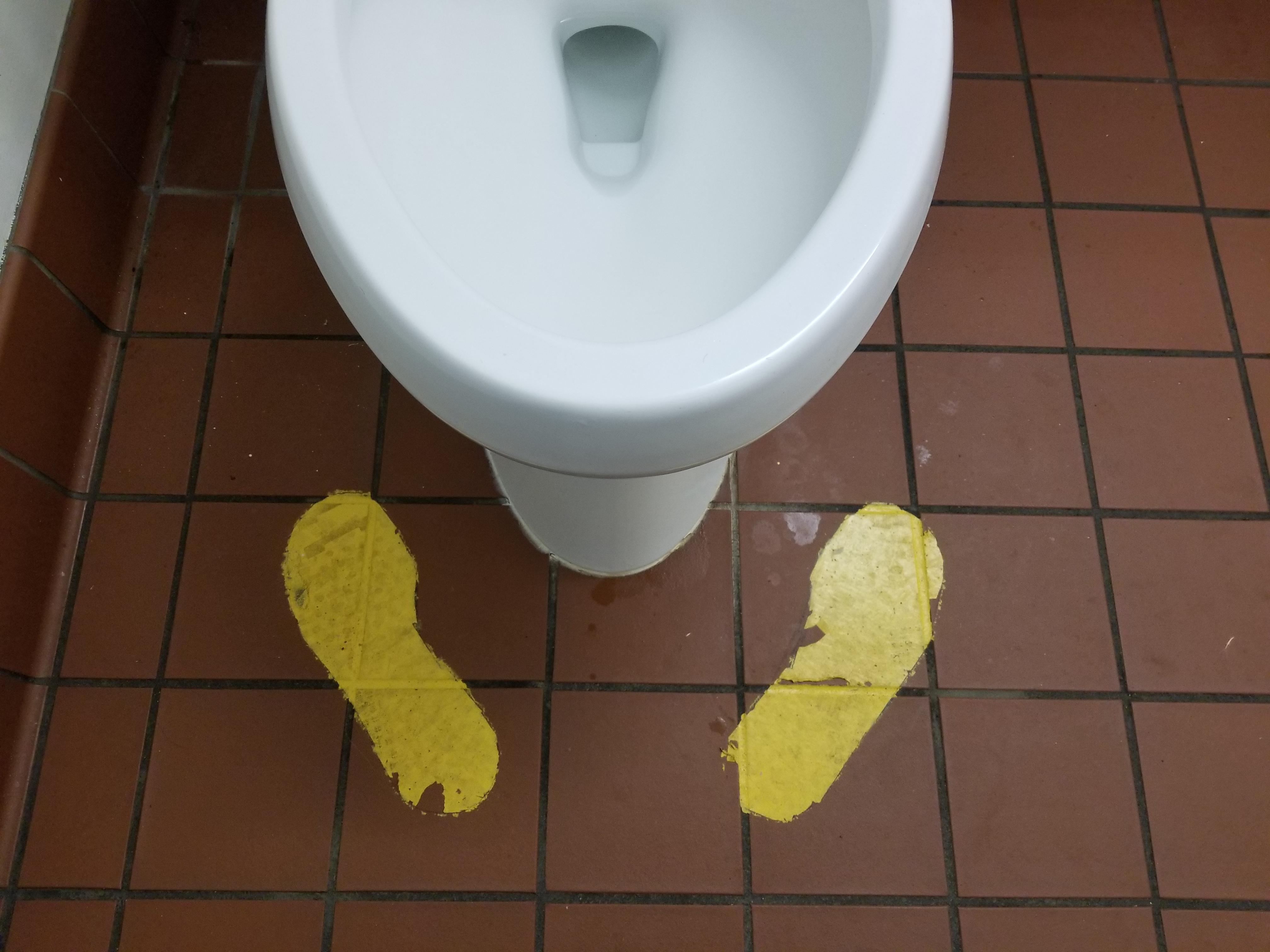 This toilet has footprints in front of it to indicate where to stand