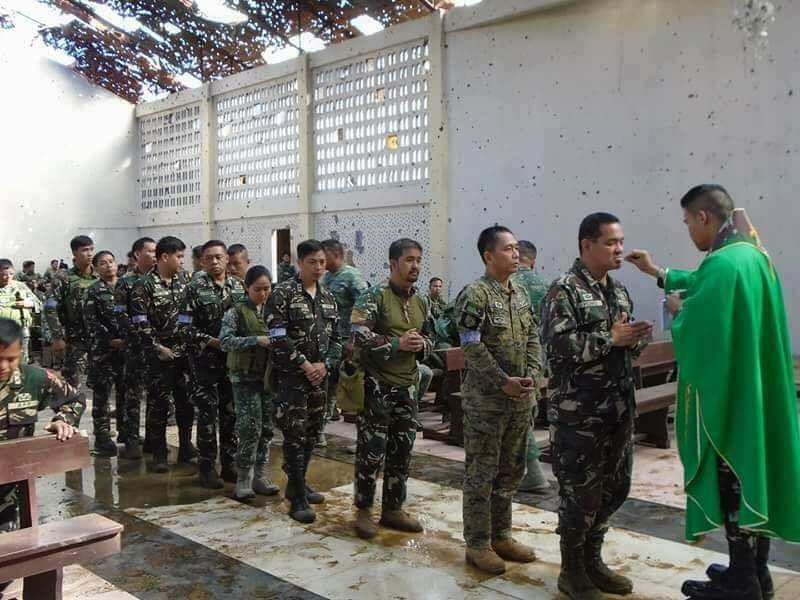 Philippine Army Chaplain giving communion to military personnel during
