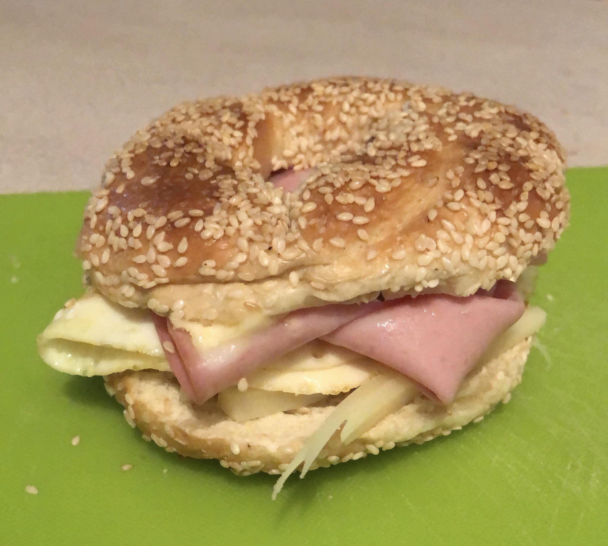 Tasty bagel sandwich with mortadella, provolone, butter and a fried egg with salt and pepper r
