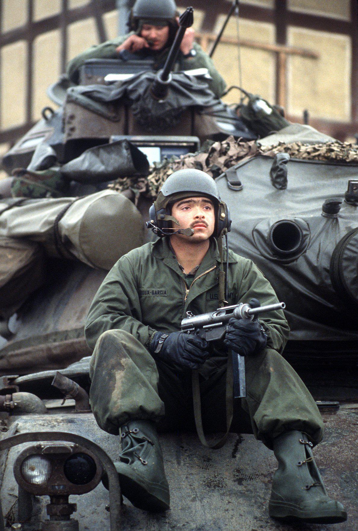 A US Army tanker holds his M3 Grease Gun atop an M60A3 MBT during