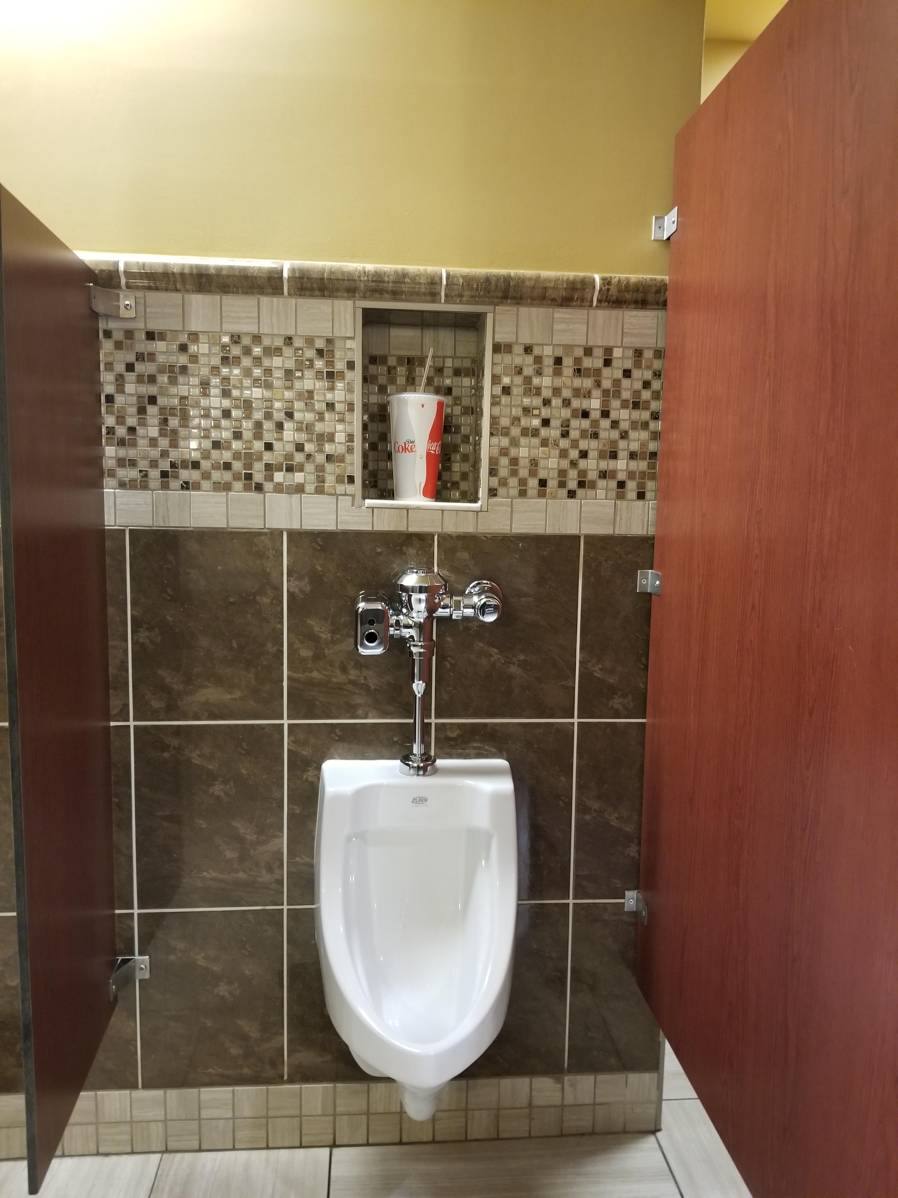 this movie theater has space for your drinks while using the urinal