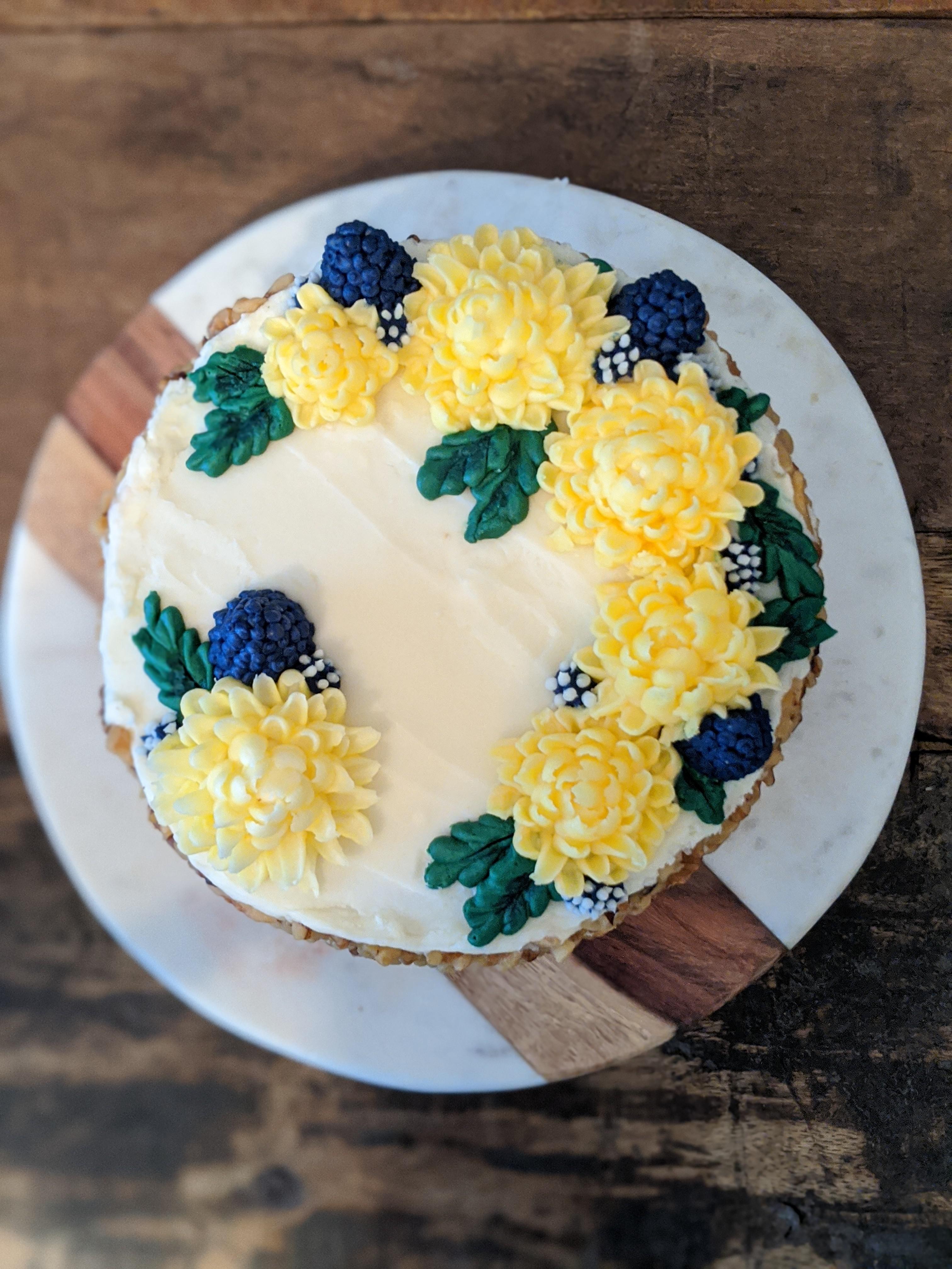 Coconut carrot cake with chrysanthemum flowers and berries piped out of