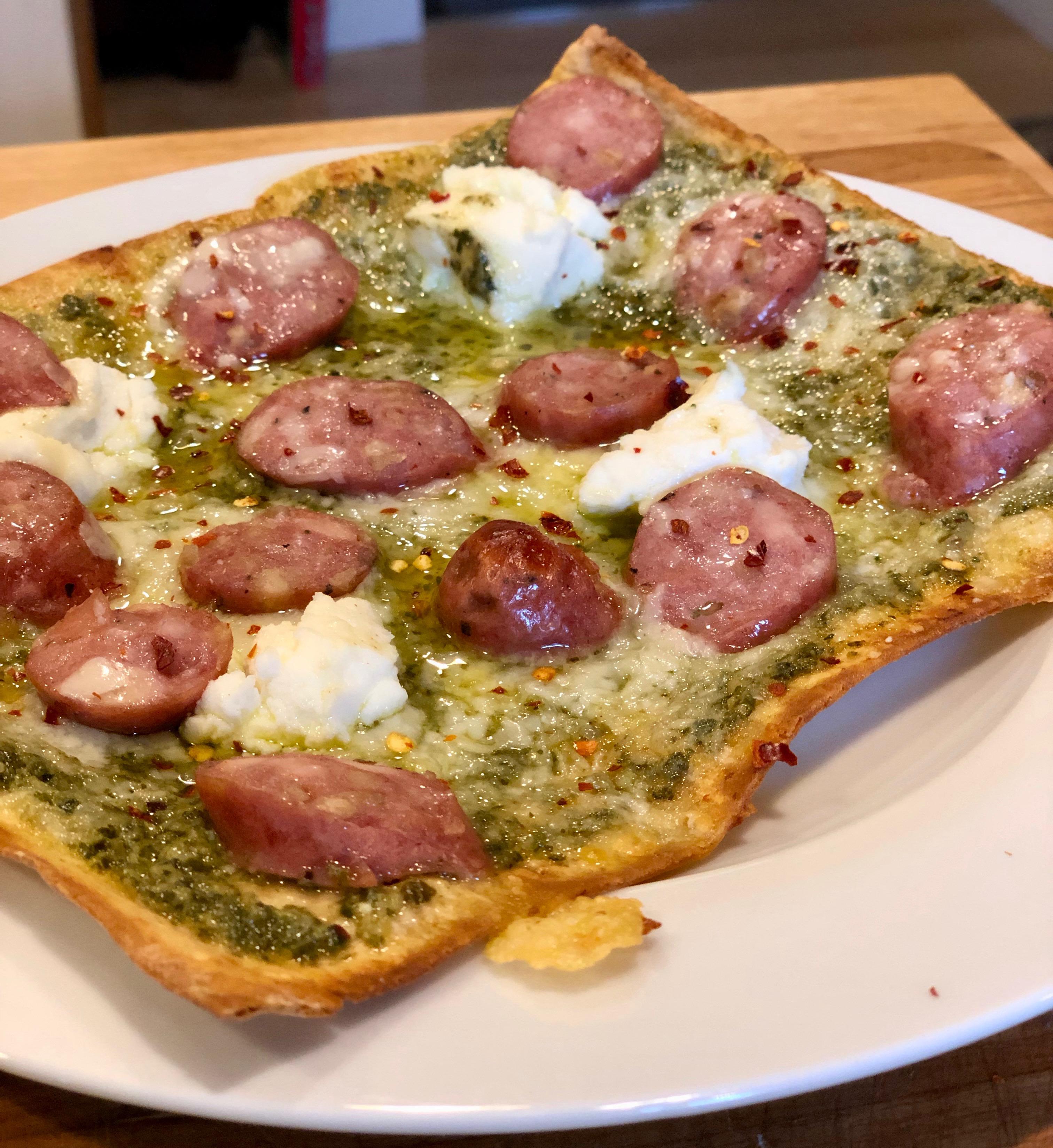 Flatbread pizza with pesto, chicken apple sausage, mozzarella, and