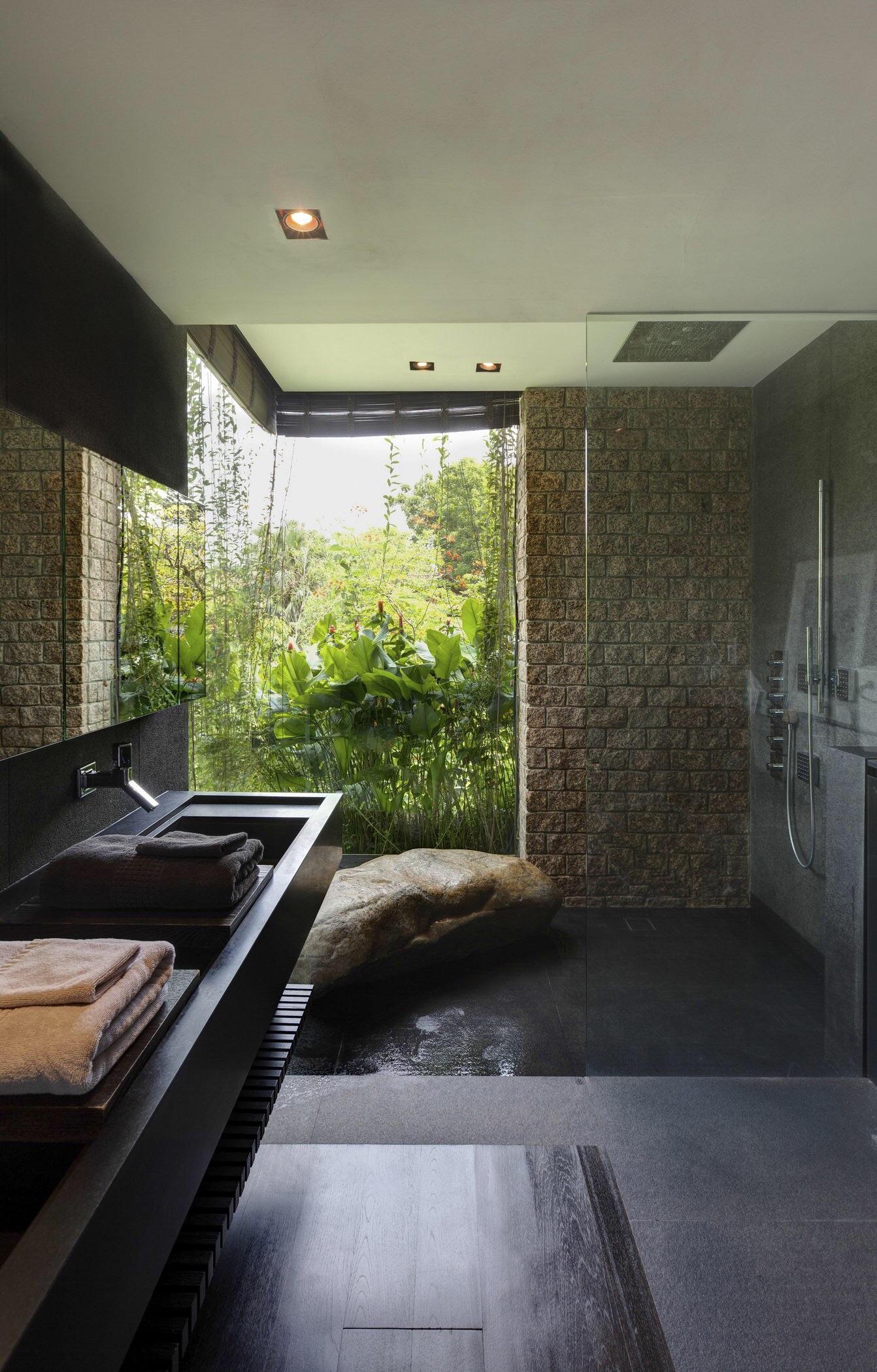 Bathroom features a large window with garden view and a sitting rock in