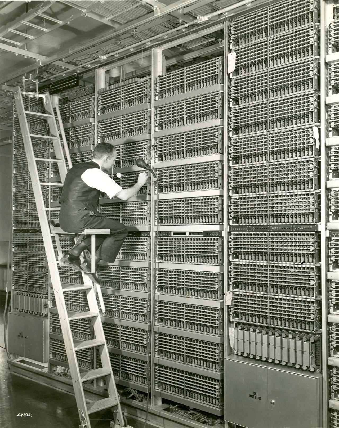 A technician doing maintenance work on the electromechanical telephone