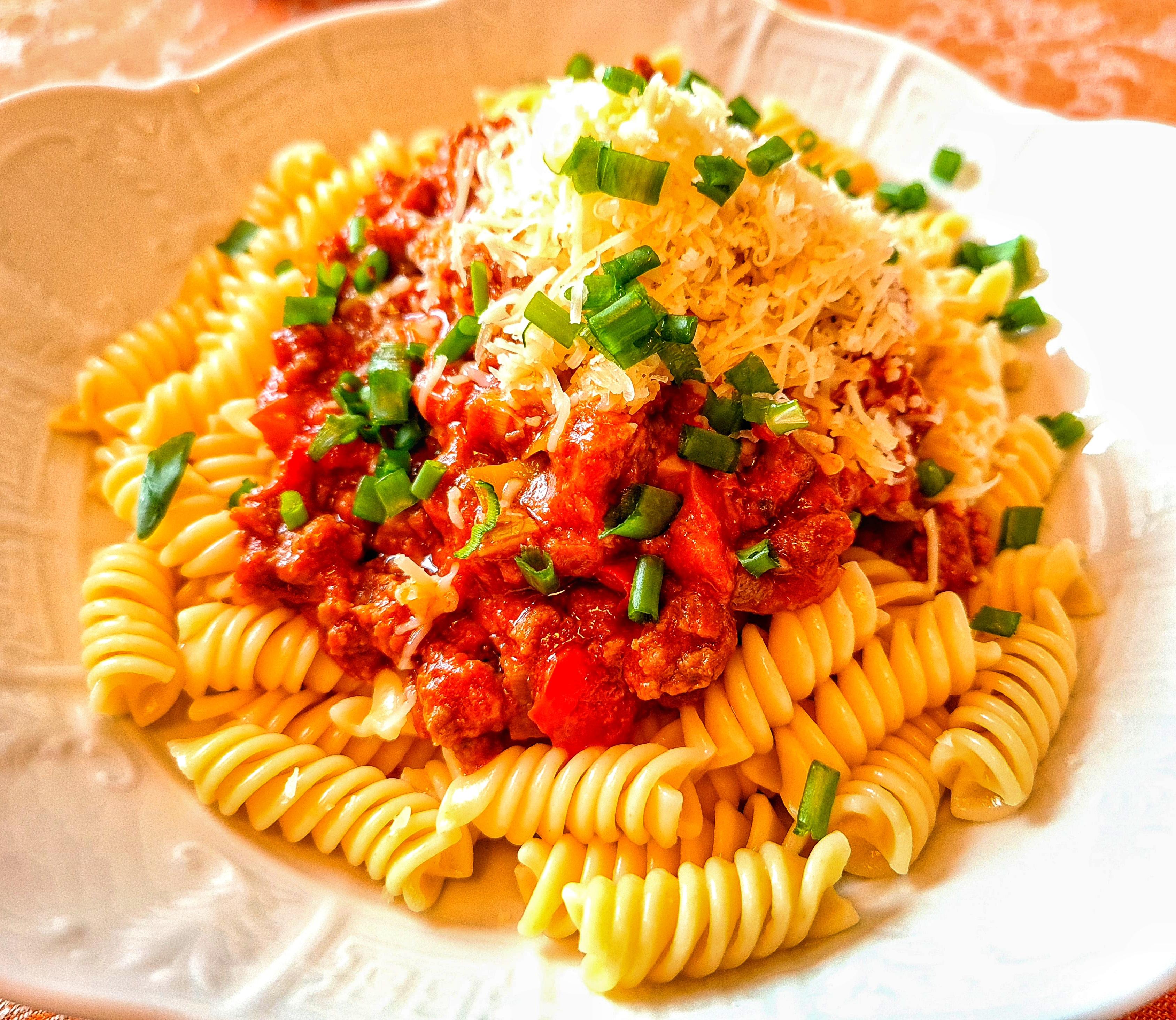 Fusilli pasta with beef ragu, veggies, grated hard cheese and some