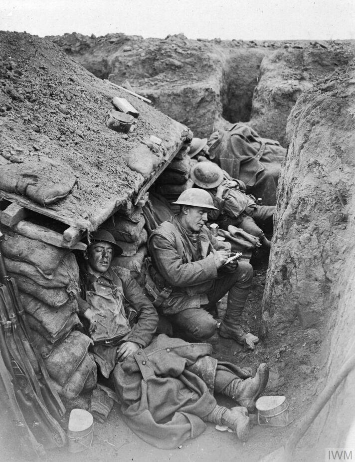 Four Canadian soldiers, sleeping and writing letters in the trenches