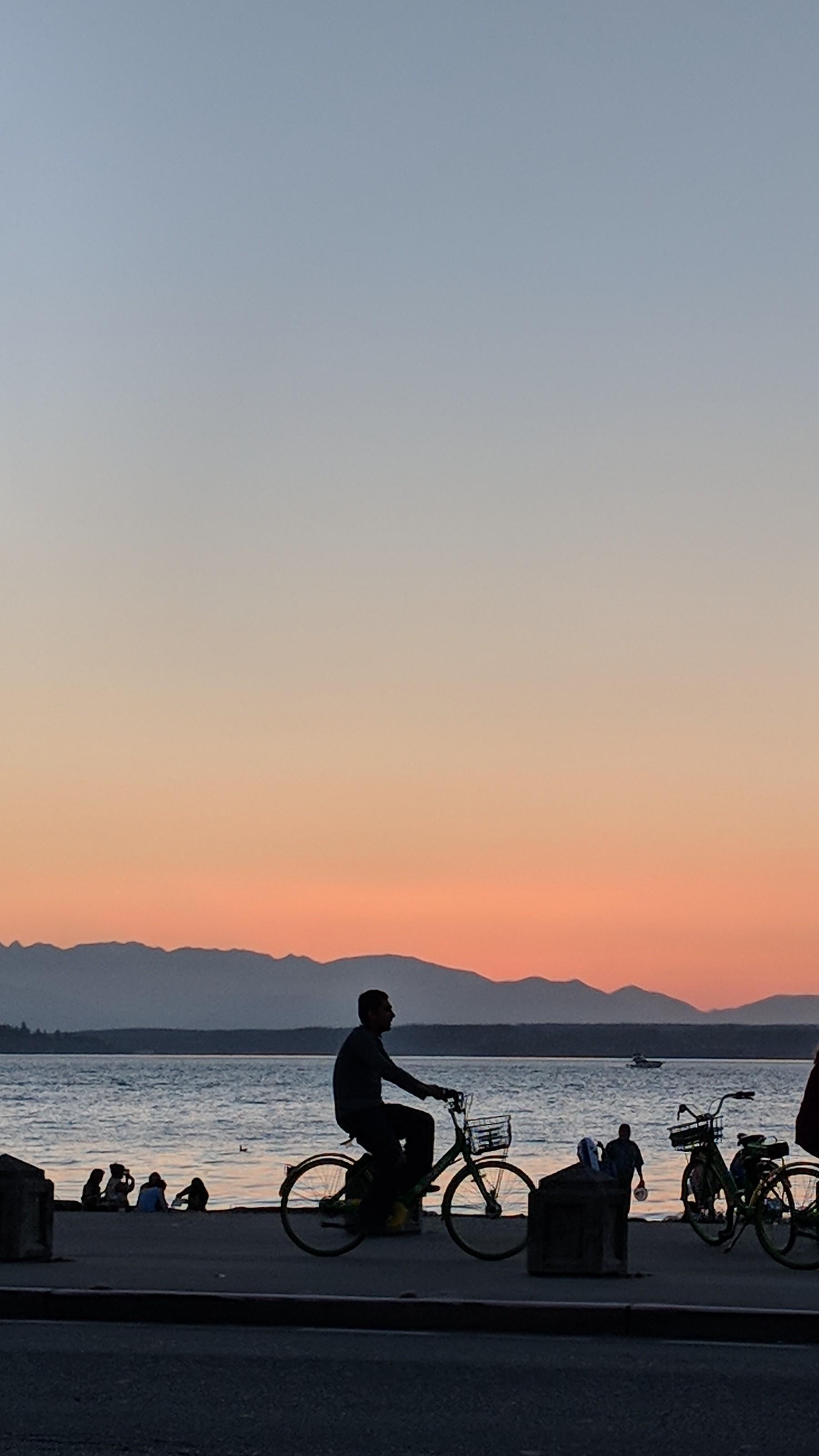 ITAP of a guy riding a bike on Alki Beach Seattle
