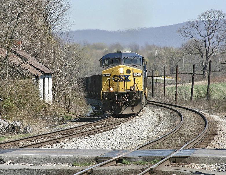 A westbound CSX train of coal empties hustles through the hamlet of
