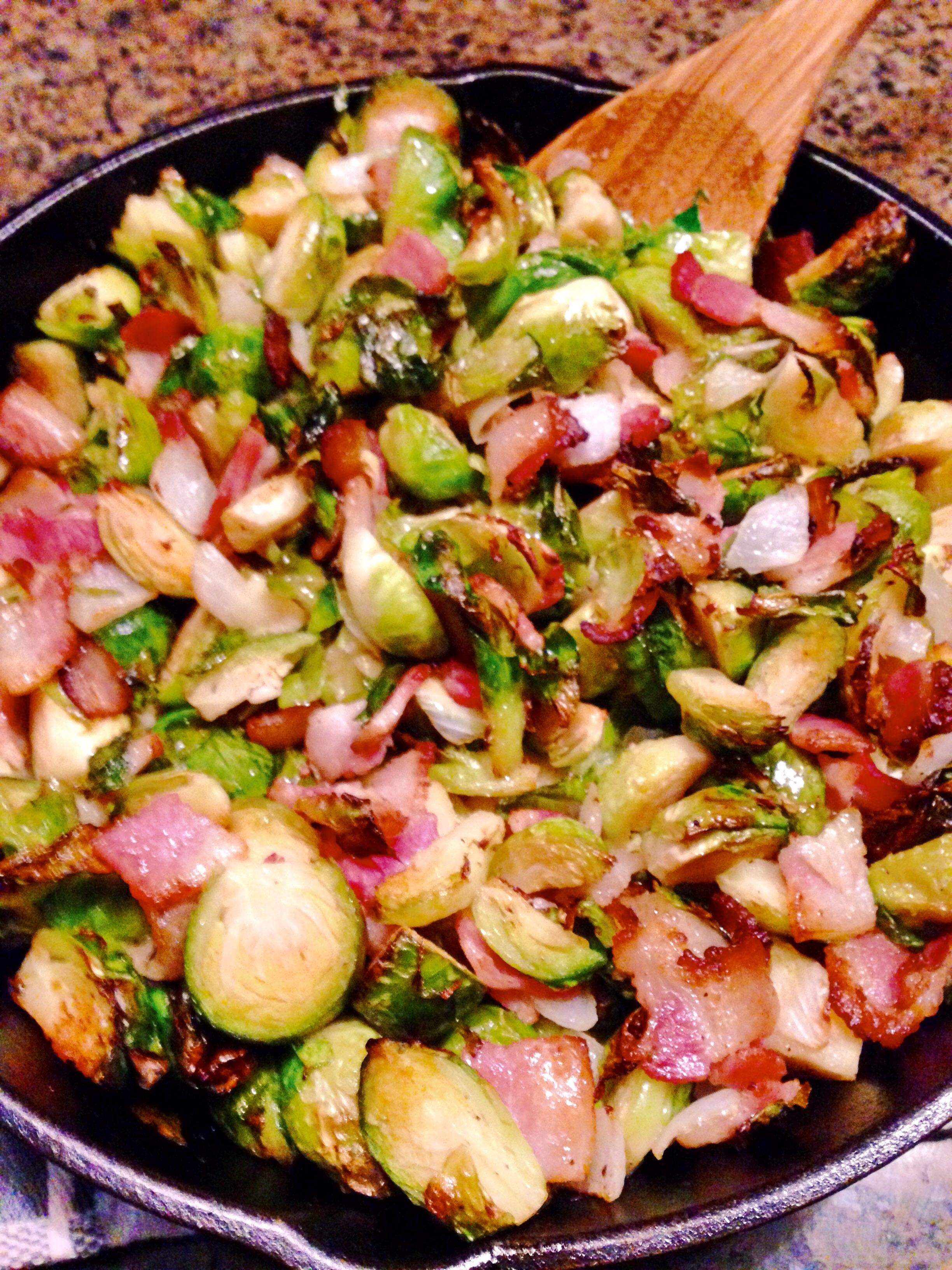 Brussel sprouts sautéed in a cast iron skillet with bacon, onion, and