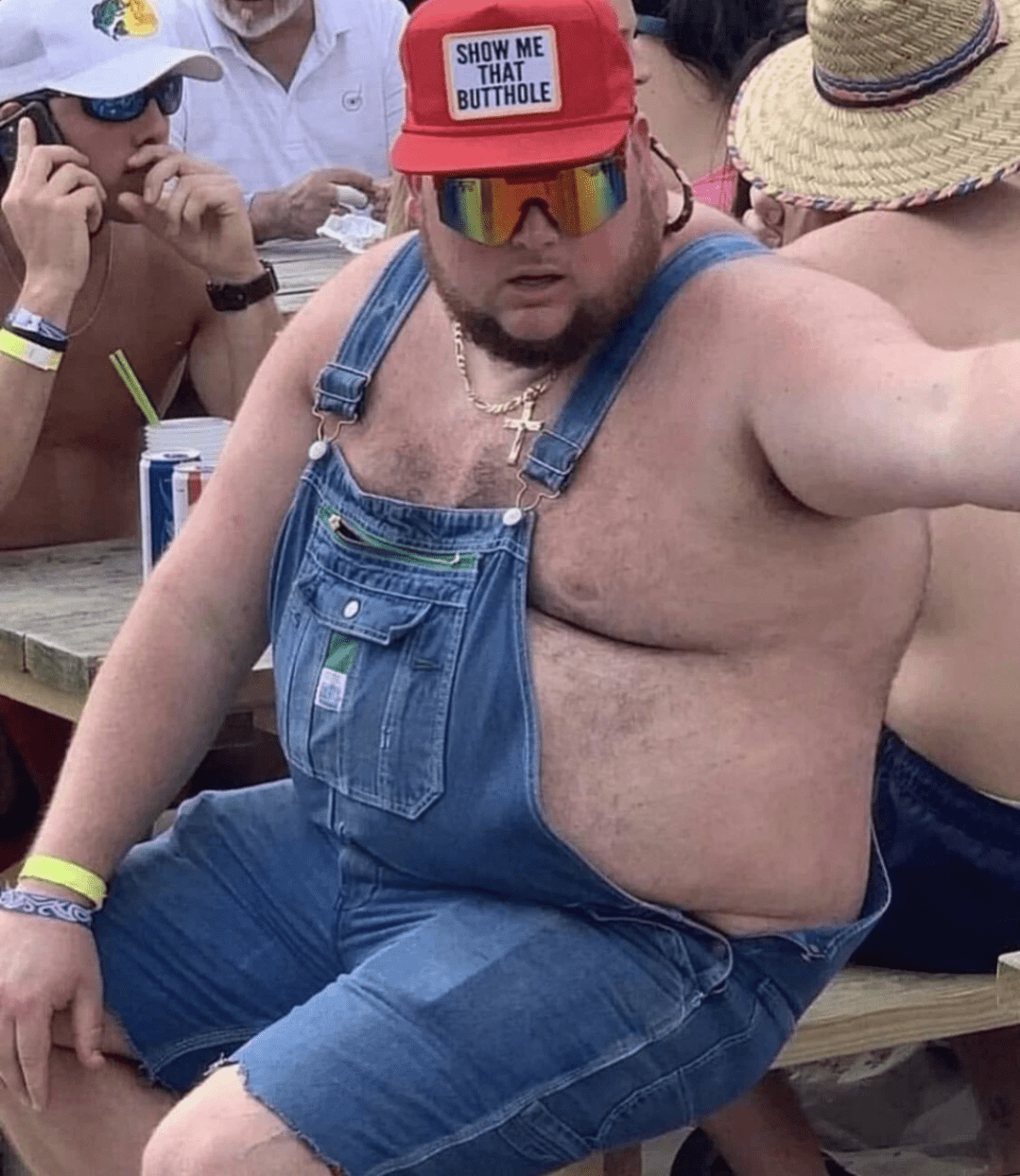 The overalls, hat, and cross necklace come together to create a stylish